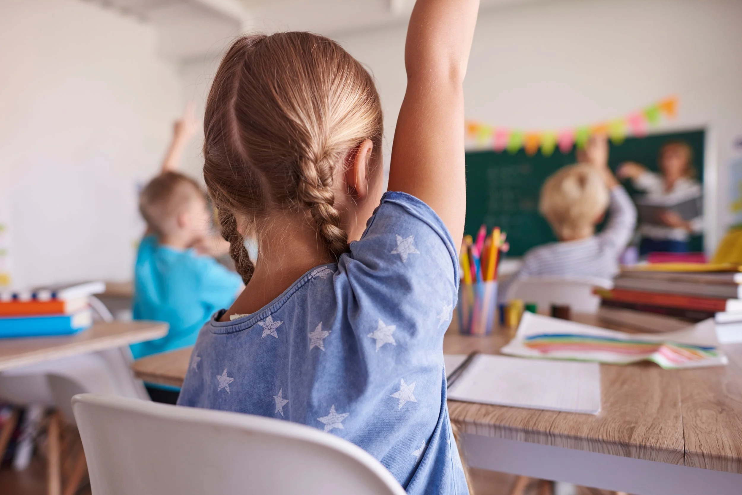 student with hands up in classroom