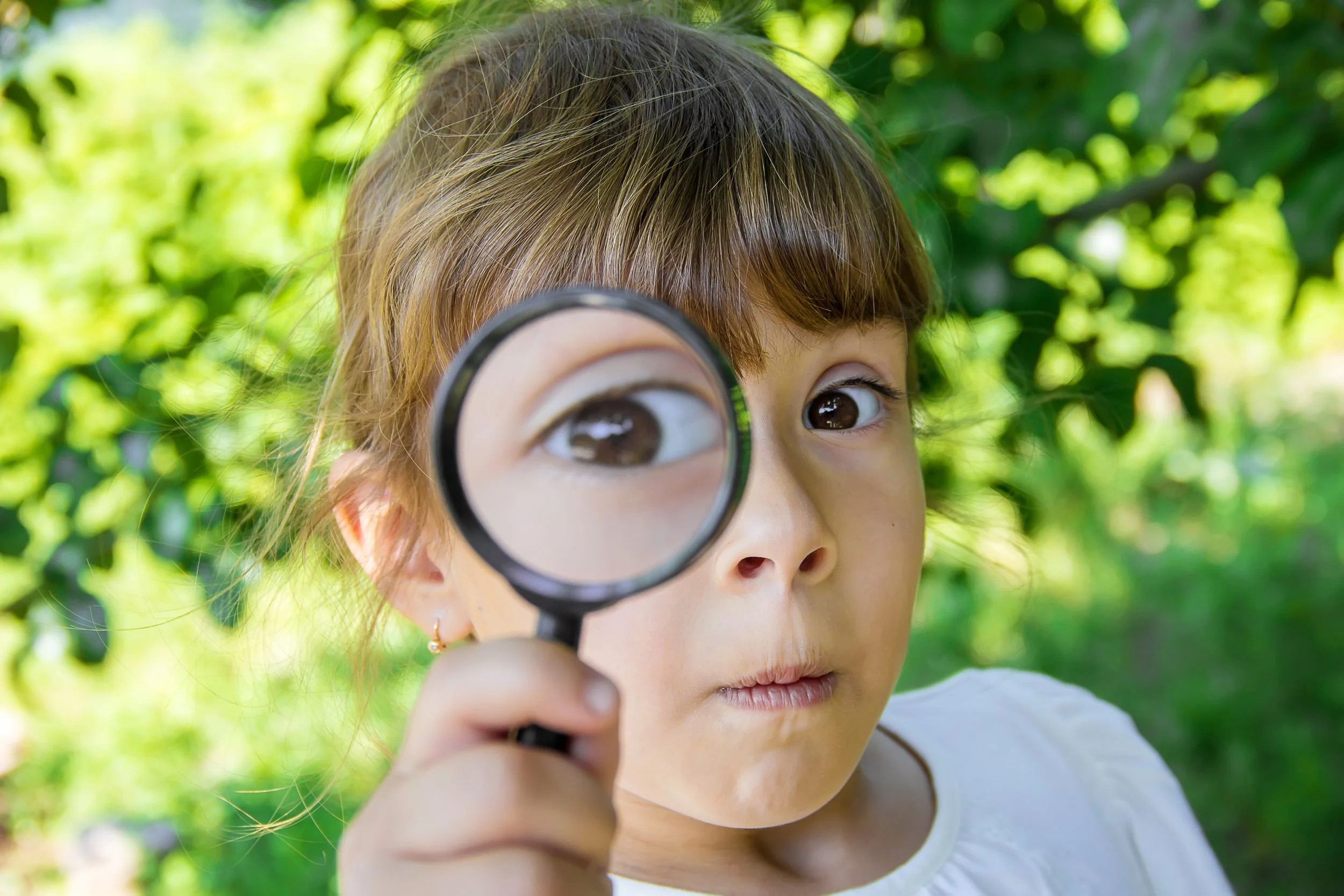 girl outdoors holding a magnifying glass