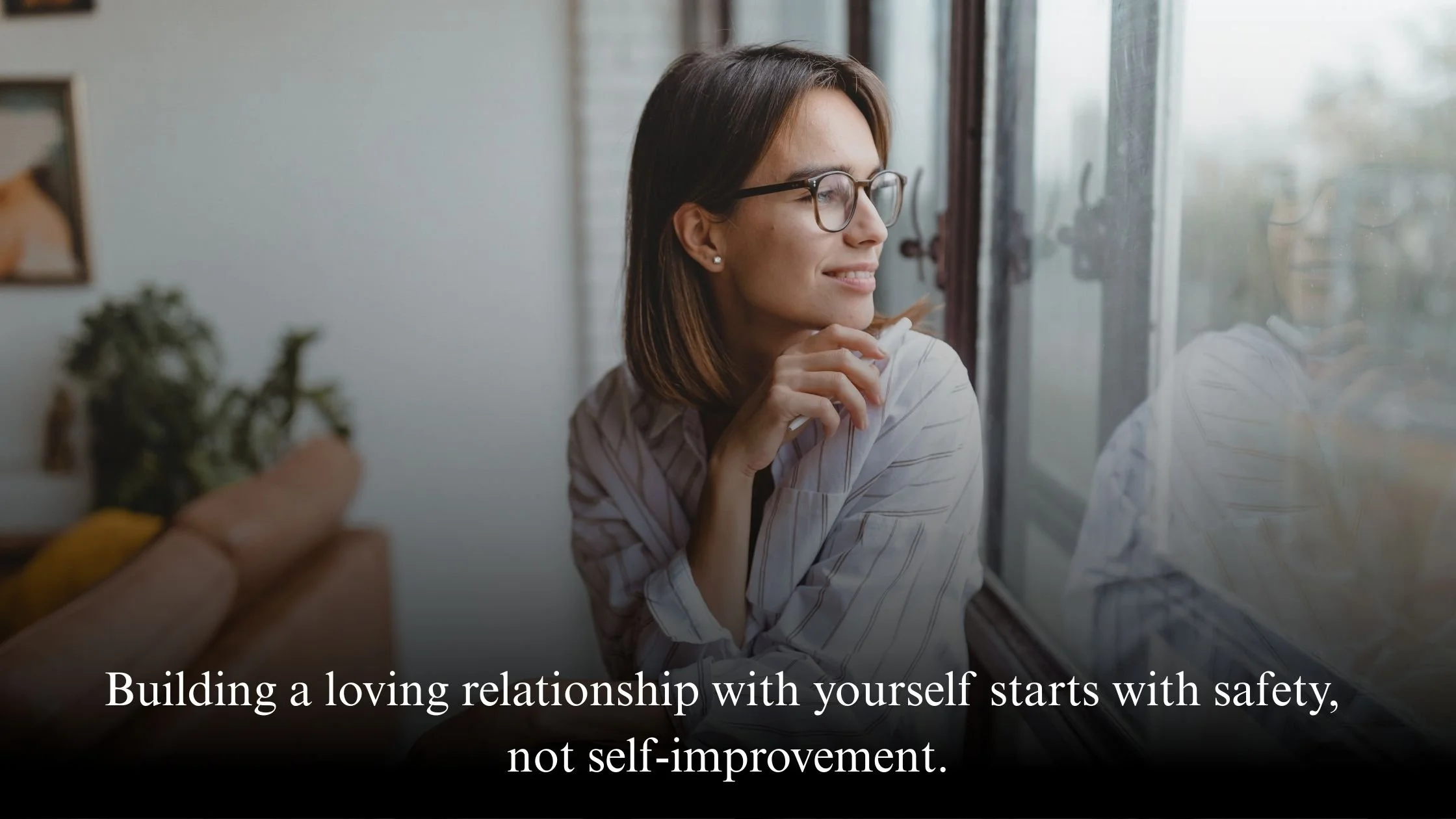 Woman sitting quietly by a window reflecting, representing building a loving relationship with yourself without self-judgment