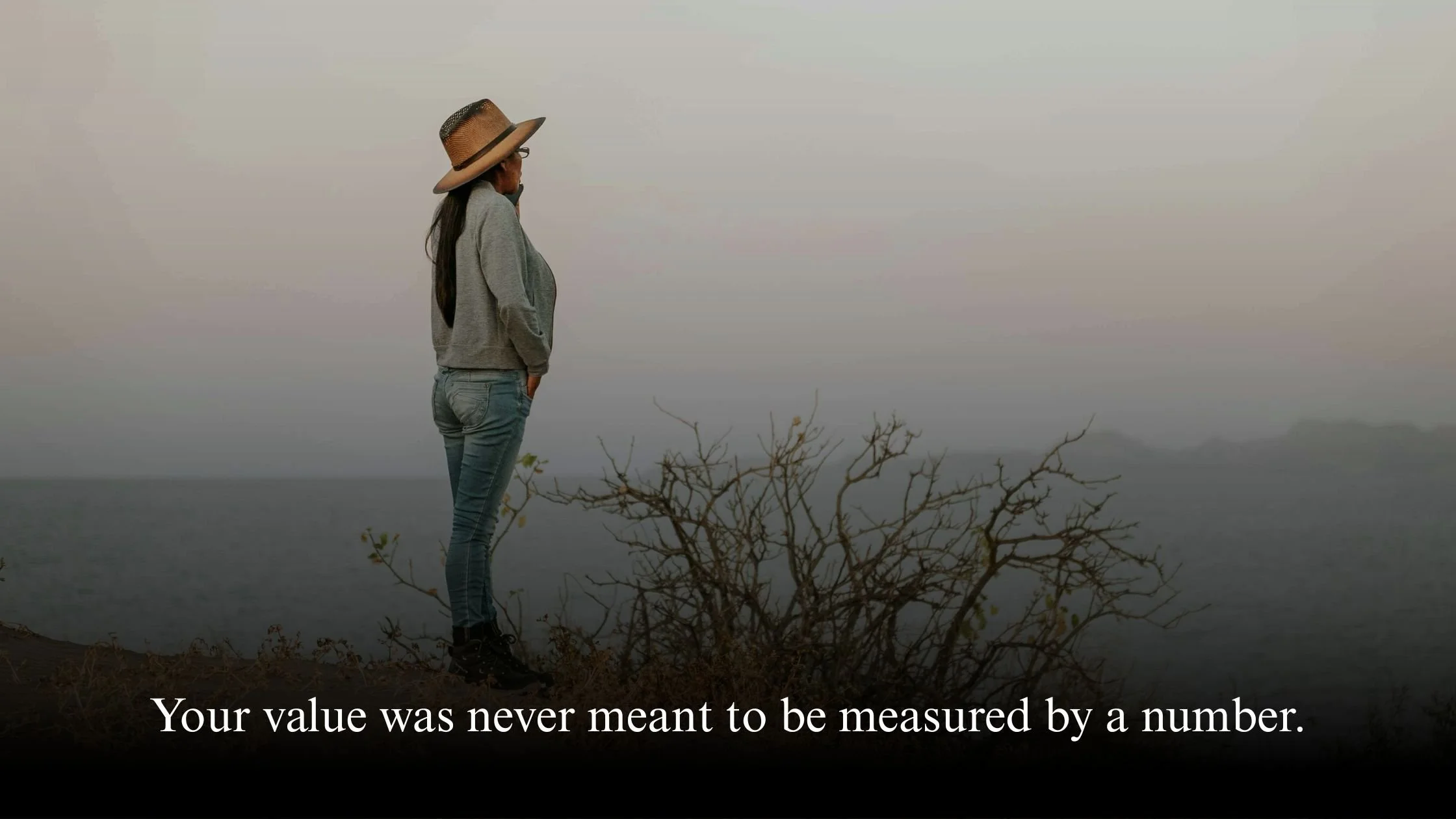 Midlife professional woman standing calmly by the sea, reflecting on career and self-worth beyond salary