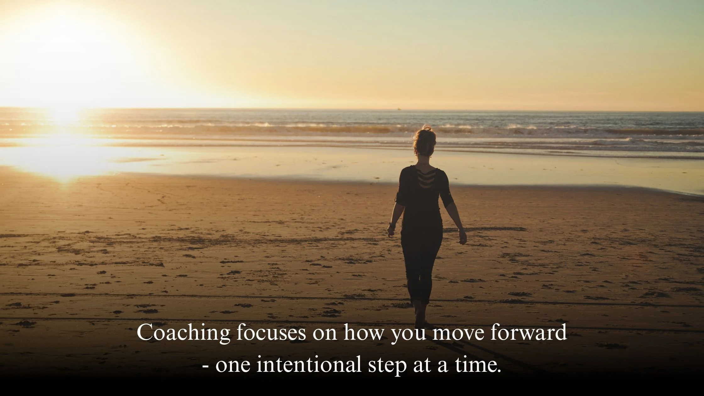 Woman walking along a coastal path, facing forward toward the horizon, symbolising present-focused personal growth through coaching.