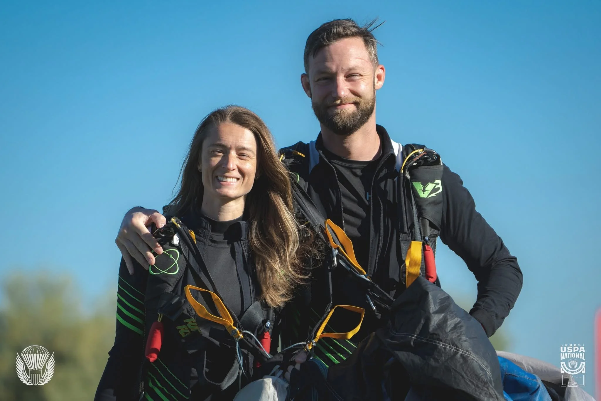 A skydiving team smiling as they walk back from the landing area after a jump.
