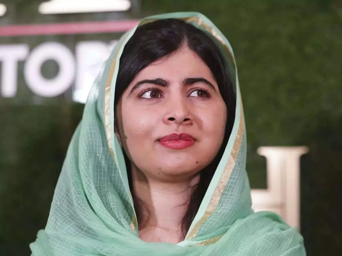 A woman with dark hair and a light green headscarf looking to the side.