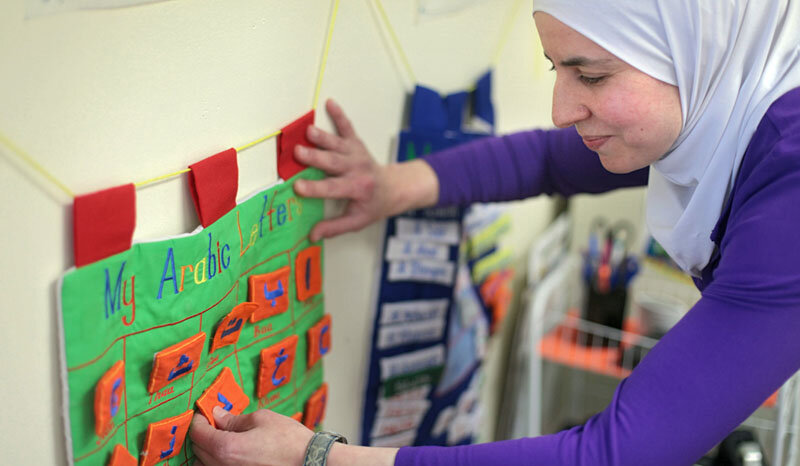 Syrian-born teacher Dania Habboub arranges a chart of Arabic letters after class in Cedar Rapids, Iowa.    Photo Credit: Daniella Cheslow. 