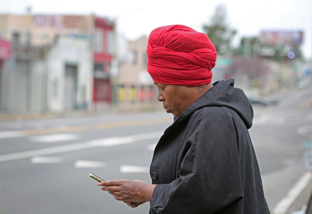 Regina Evans checks her smartphone for messages while standing on a section of International Boulevard in Oakland known as The Track.