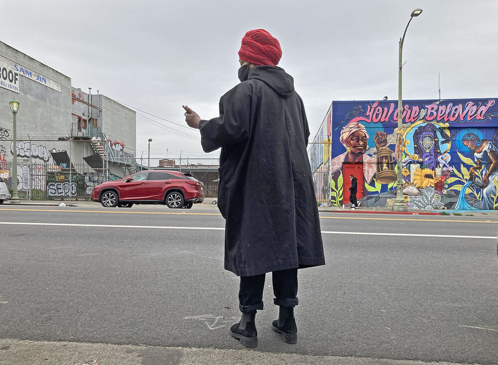 Regina Evans checks her smartphone for messages while standing on a section of International Boulevard in Oakland known as The Track.