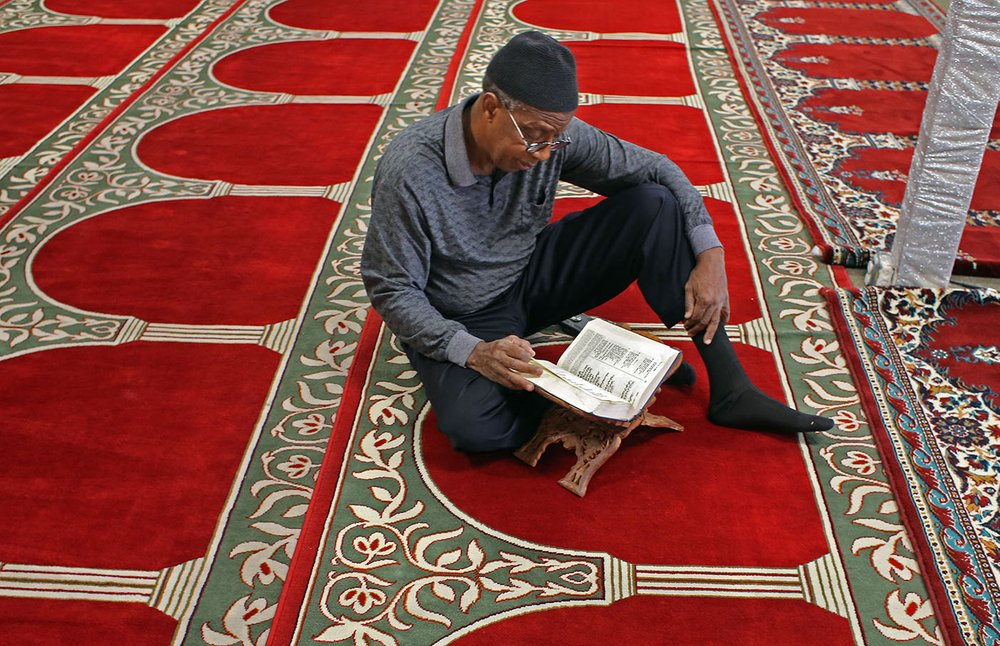 Abdul reads the Quran while sitting on the floor of the mosque he attends in Oakland.