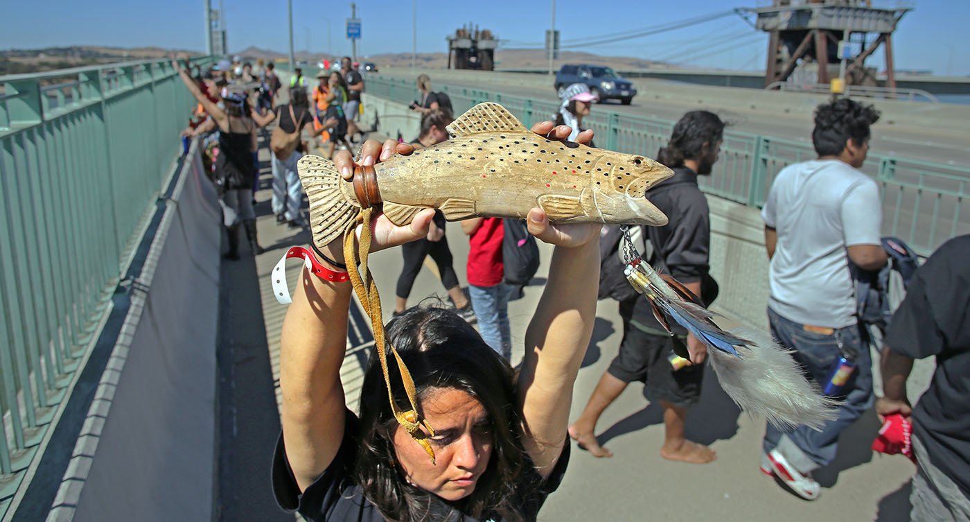  Carquinez Strait, CA — Desirae Harp (Mishewal OnastaTis Nation) holds up a wooden salmon baton as the Run4Salmon crosses over the Benicia-Martinez Bridge. September 17, 2018. Tom Levy/The Spiritual Edge 