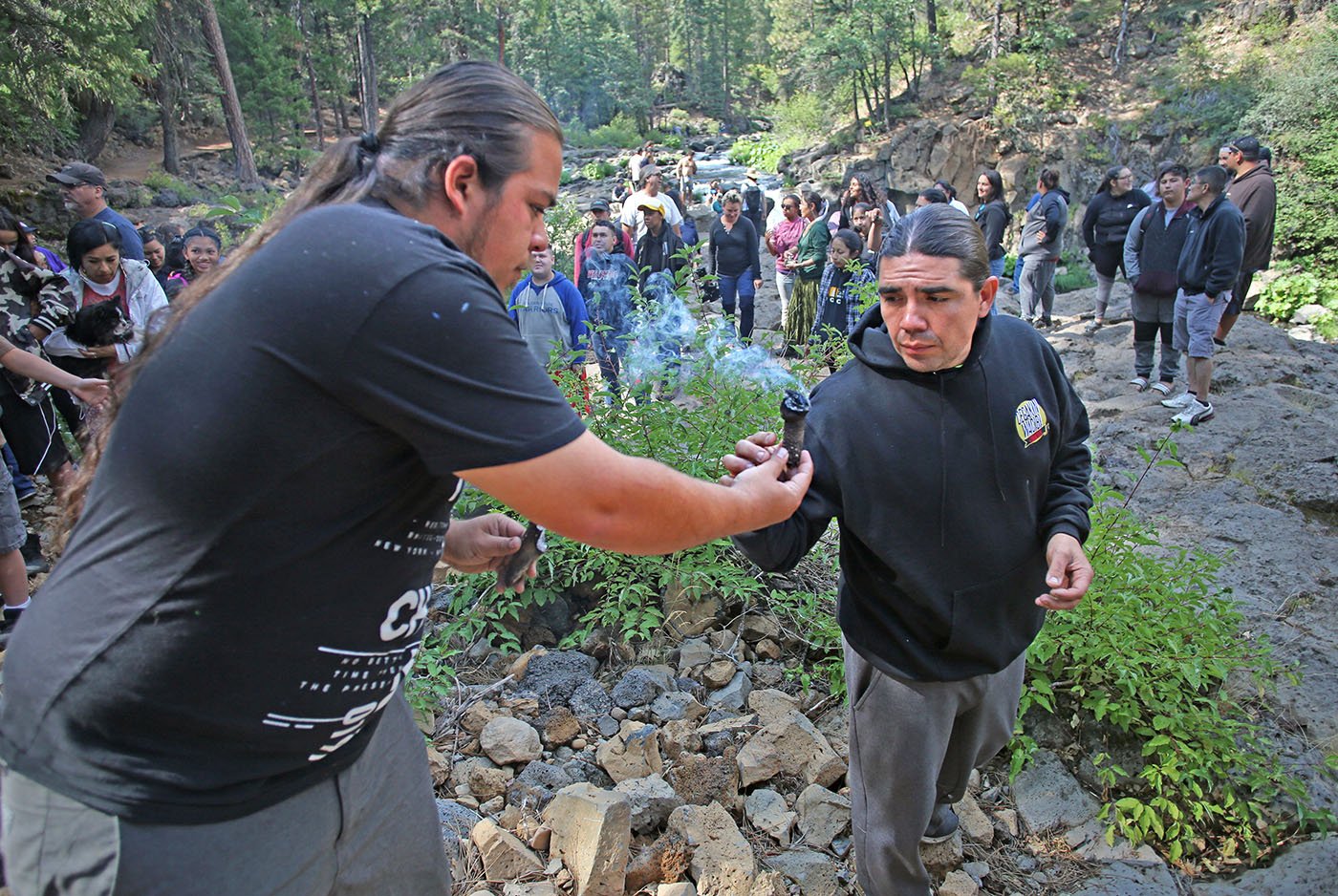  Lower McCloud River Falls, CA —  A root used for smudging is passed along. The smoke is used to purify members of the group before starting the “Salmon Challenge.” July 10, 2019. Tom Levy/The Spiritual Edge 