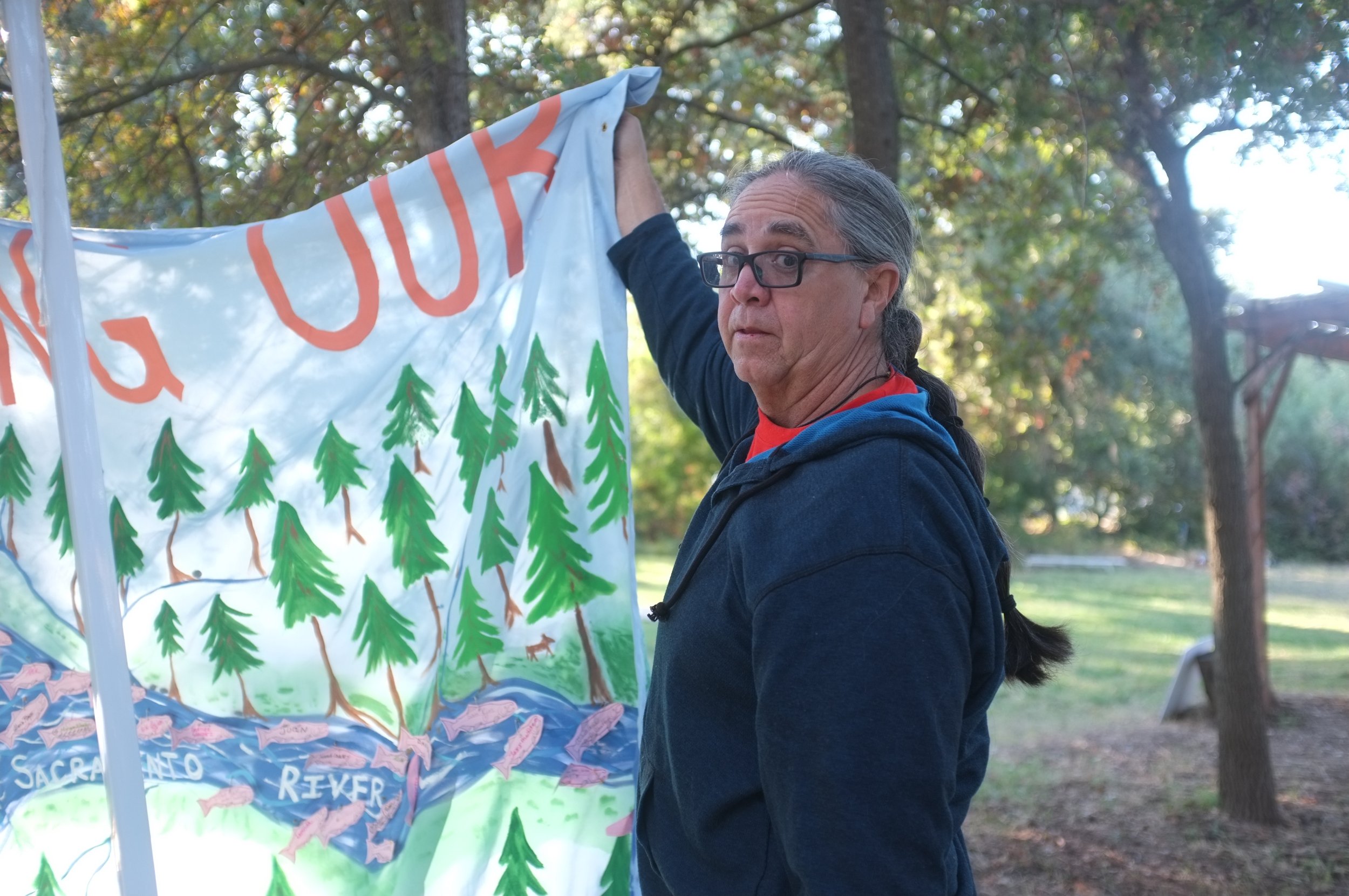  Chico, CA — Dr. Dennie Schulteis hangs a banner before a Run4Salmon concert after the first day of biking. September 23, 2018. Judy Silber/The Spiritual Edge 