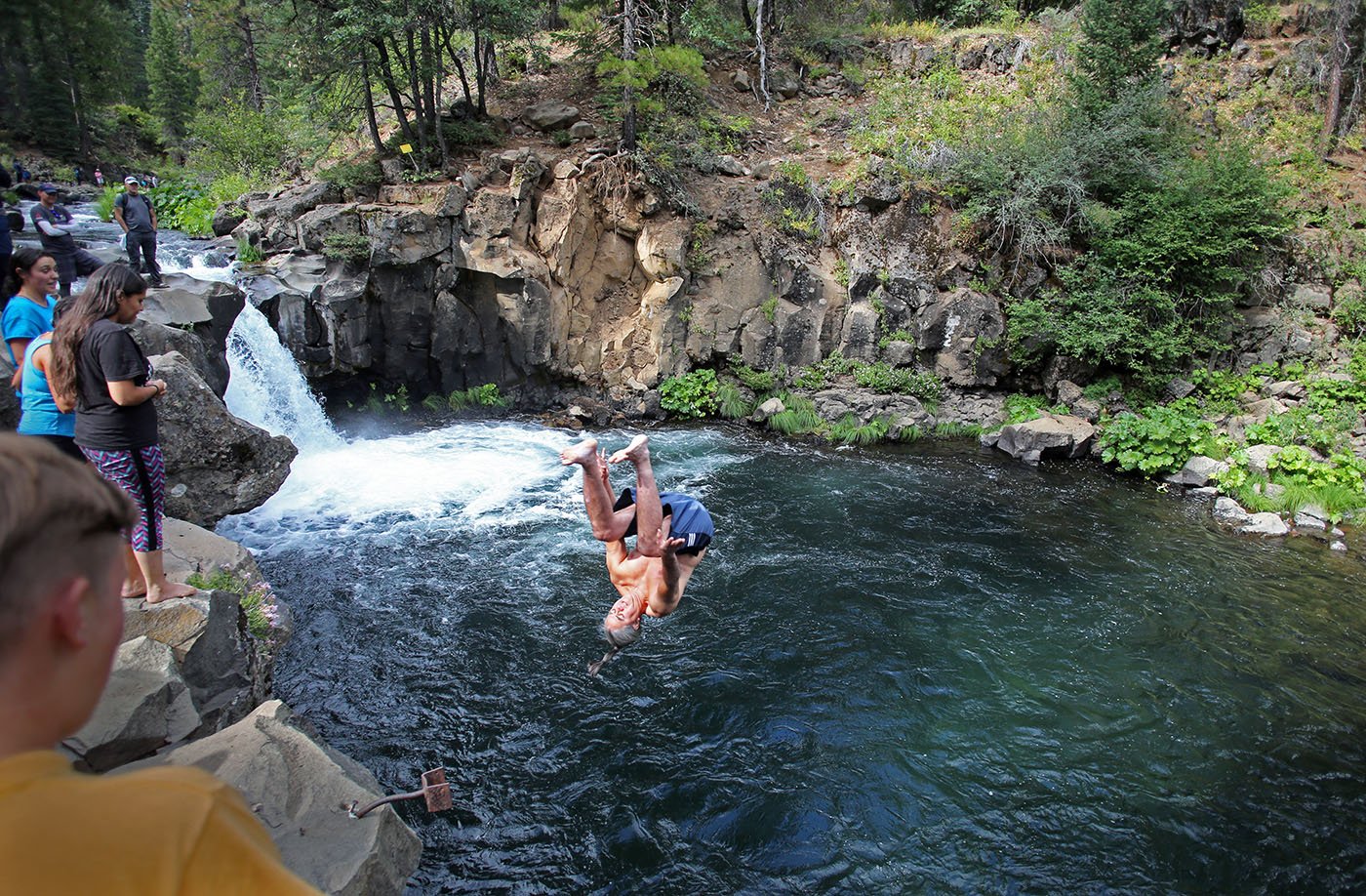  Lower McCloud River Falls, CA — Dr. Dennie Schulteis flips into a deep pool as part of a ceremony to remember the salmon that once swam here. July 10, 2019.  Tom Levy/The Spiritual Edge 