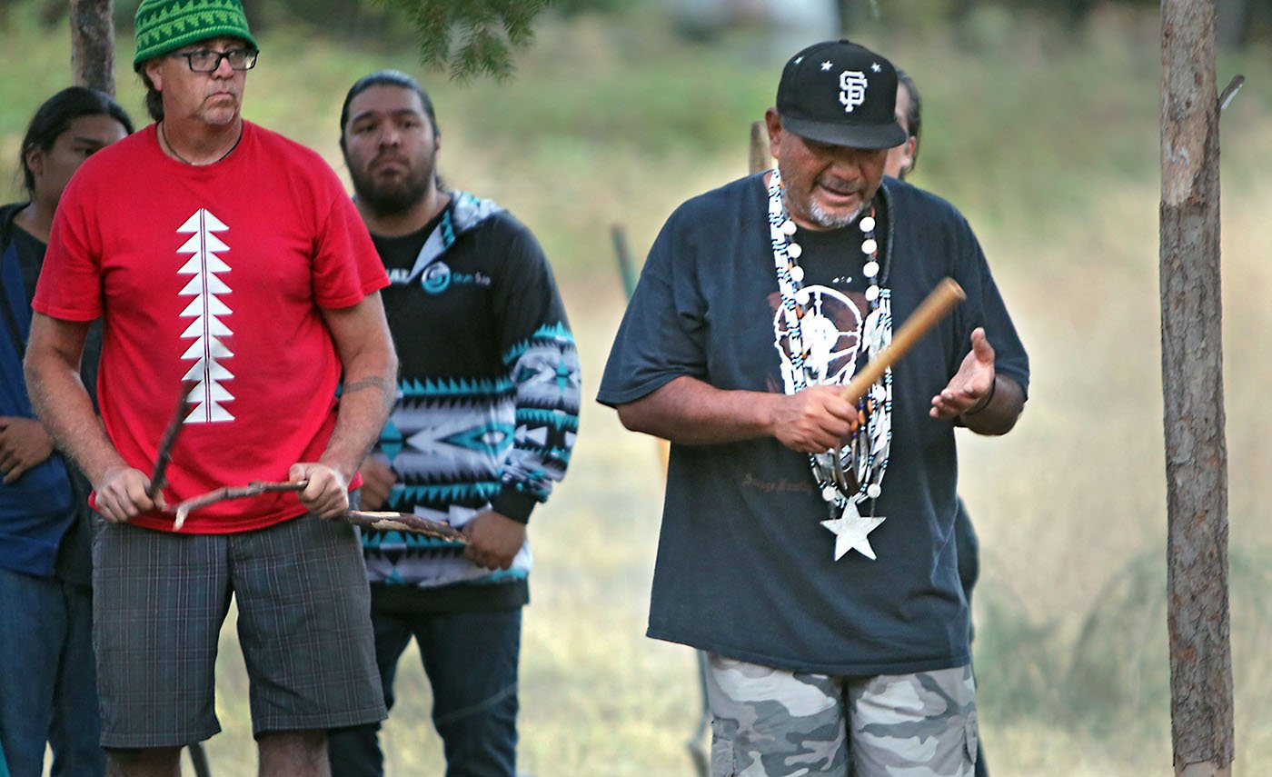  Lakehead, CA — Gary Thomas (Elem Pomo) keeps time with a clapper stick at a Run4Salmon completion ceremony on the McCloud River. Dr. Dennie Schulteis (Winnemem Wintu) stands to his side. September 30, 2018. Tom Levy/The Spiritual Edge 