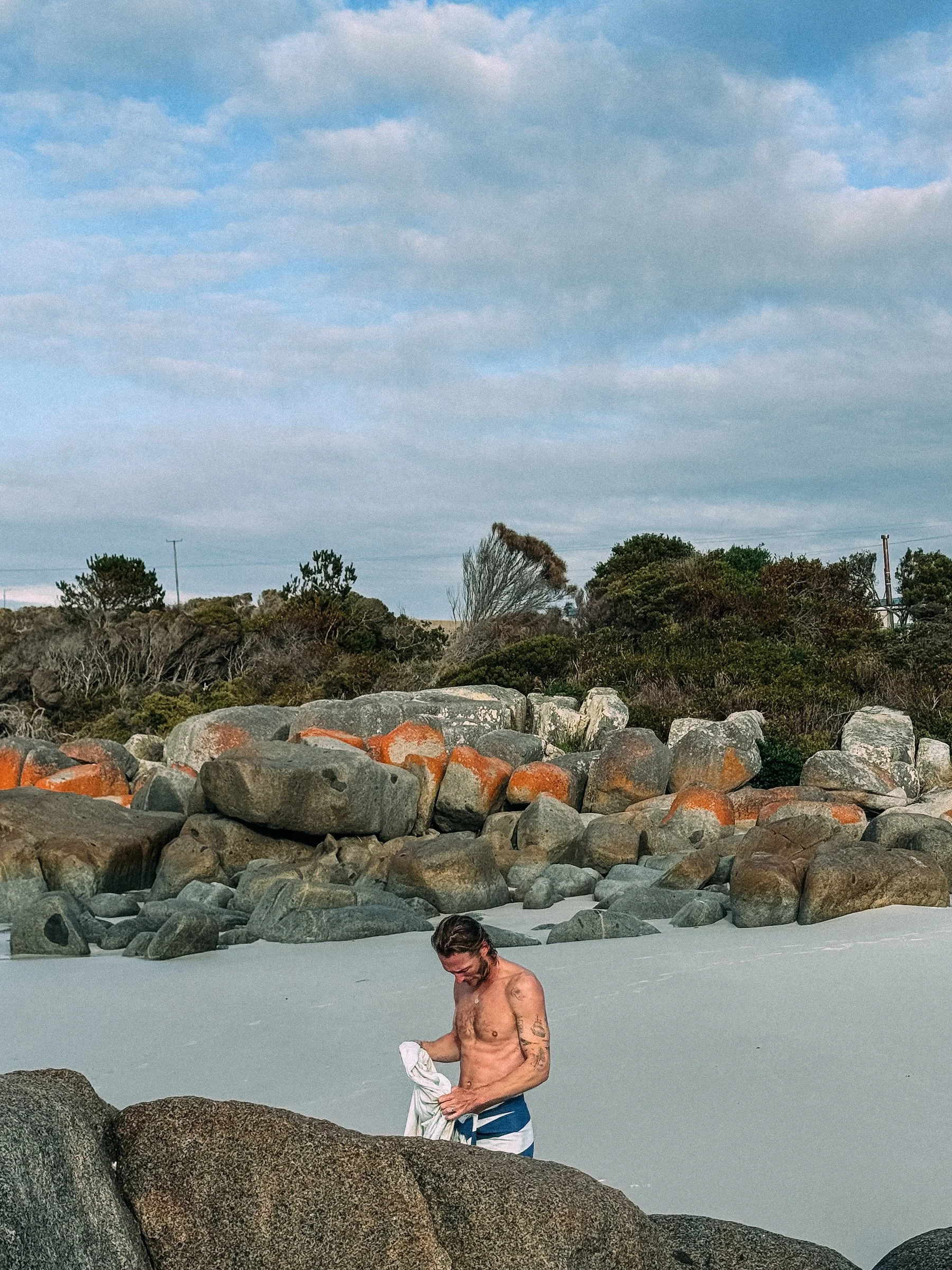 Orange lichen-covered rocks and white sand at the Bay of Fires