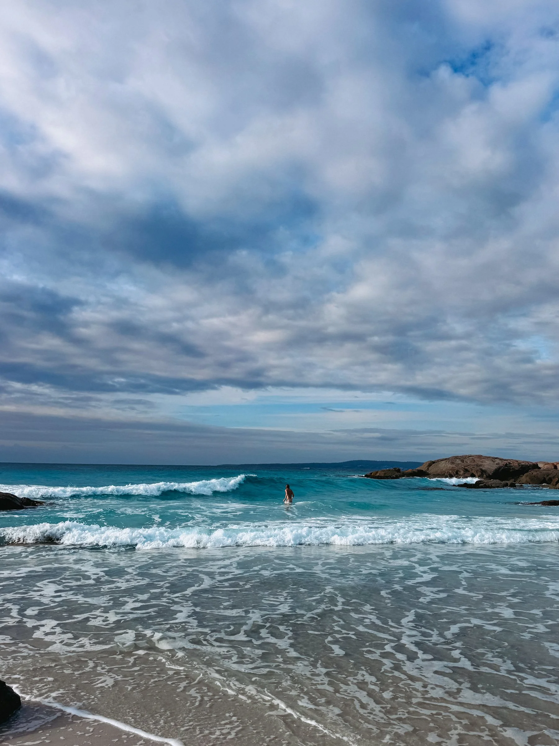 Orange lichen-covered rocks and white sand at the Bay of Fires