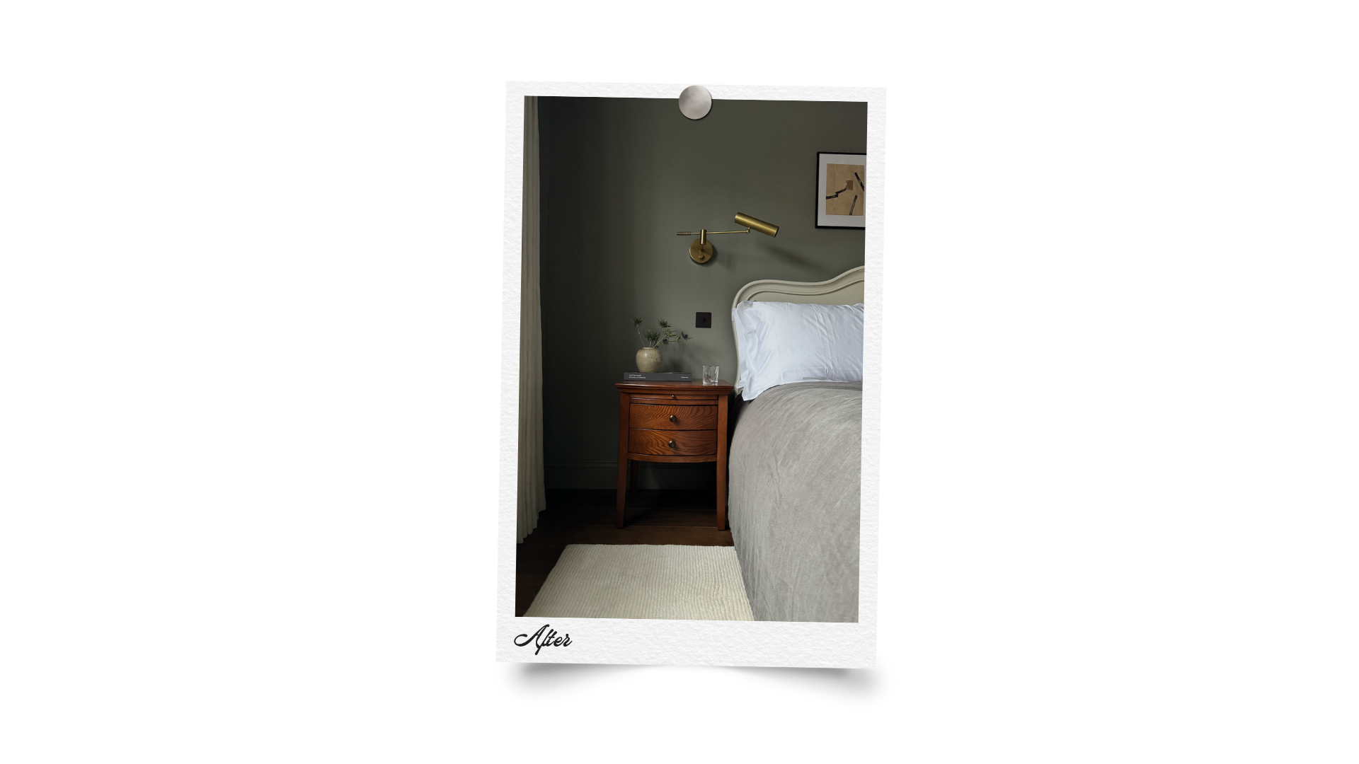 A tidy bedroom with a green wall, a wooden nightstand, a plant in a ceramic vase, a glass of water, a white bed with a beige bedspread, a wall-mounted brass reading lamp, and framed artwork on the wall.