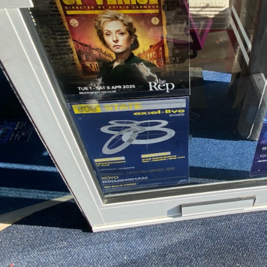 Poster for a theatrical show featuring a woman with blonde hair, and a sign for an exam called BTEC, Exel-ius 2025, with the location in Birmingham.