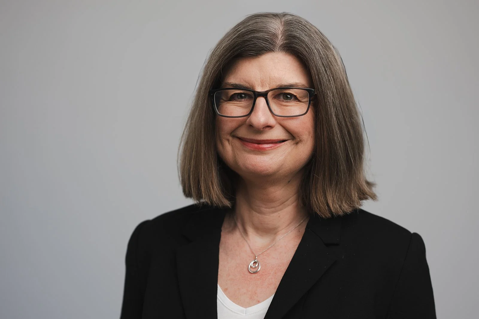 A photo of Maeve Walash a woman with light brown hair wearing black glasses and a black jacket