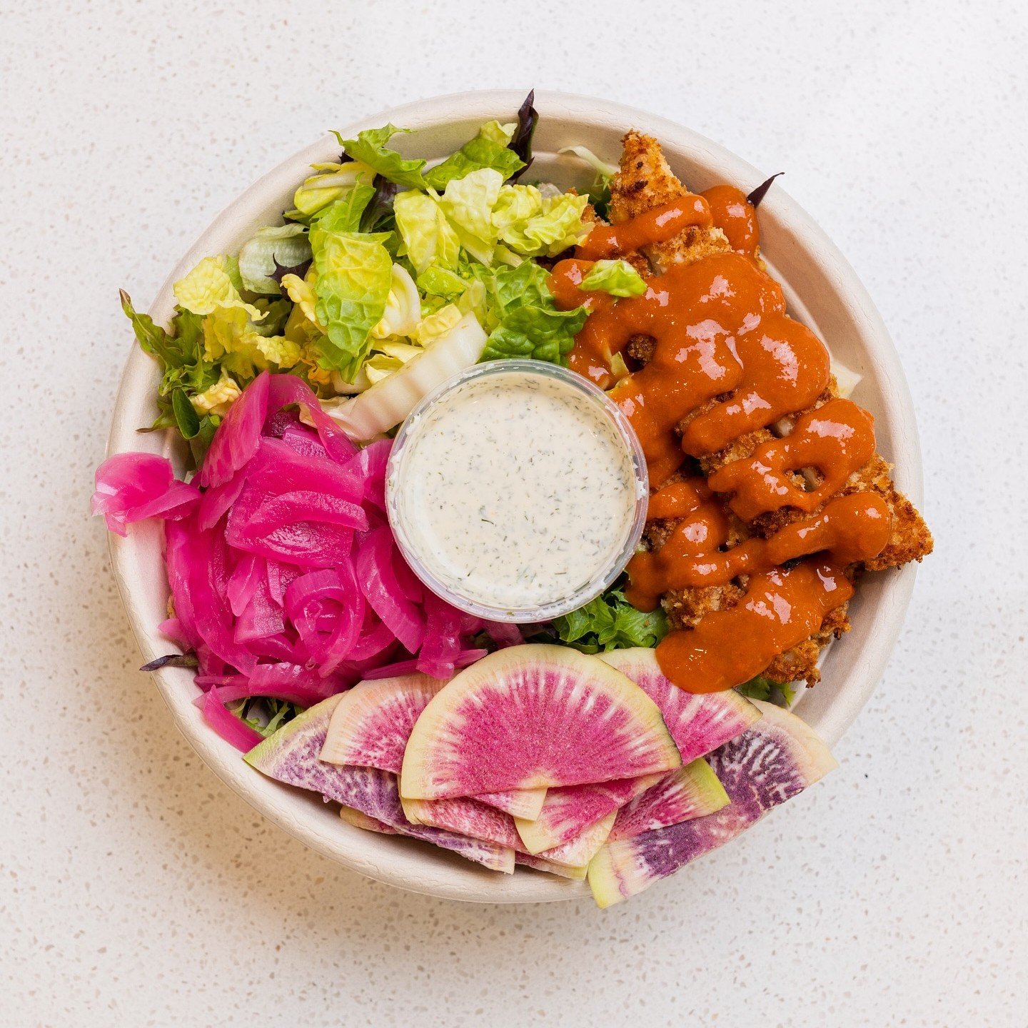A healthy, colorful Hot & Crispy salad bowl with radish, napa cabbage, pickled red onion, etc.