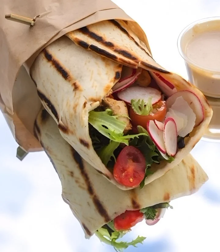 Radish Kitchen’s wrap filled with tomatoes and radish slices, covered in brown paper.