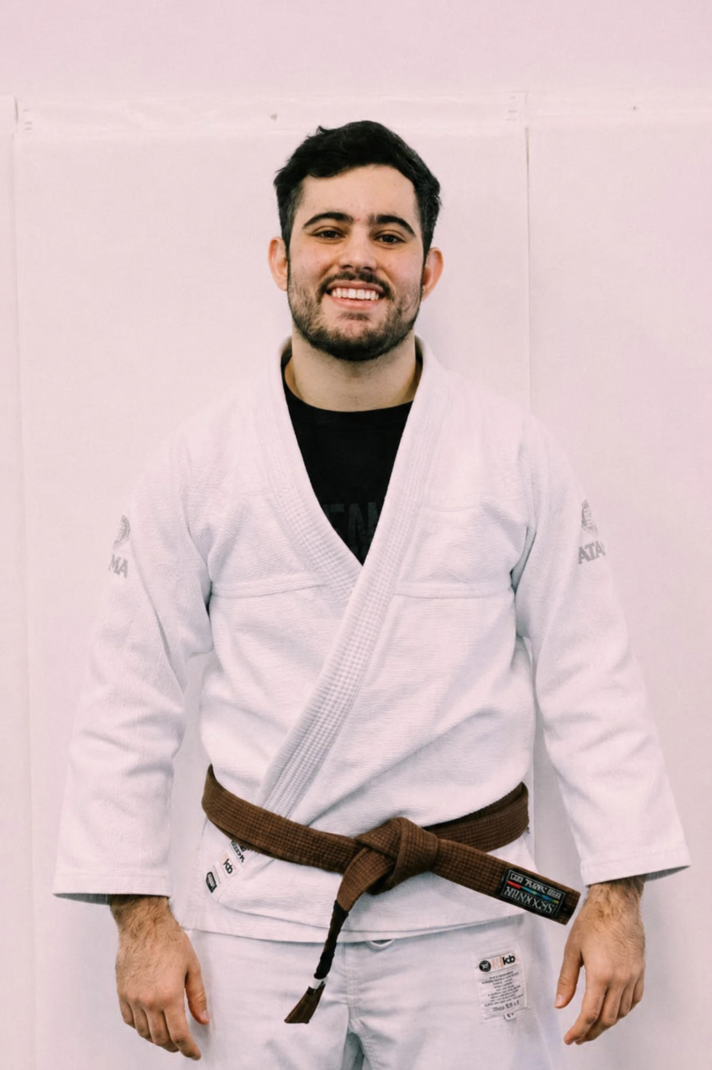 Person in a white martial arts gi with a purple belt, smiling.