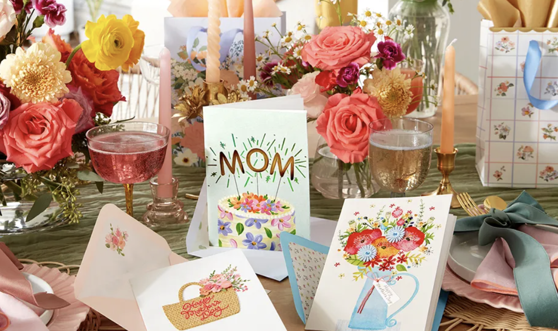 Vibrant Mother's Day table setting with floral cards, bouquets, and pink drinks.