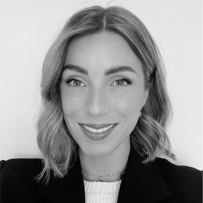 A woman with shoulder-length wavy hair smiling at the camera in black and white.