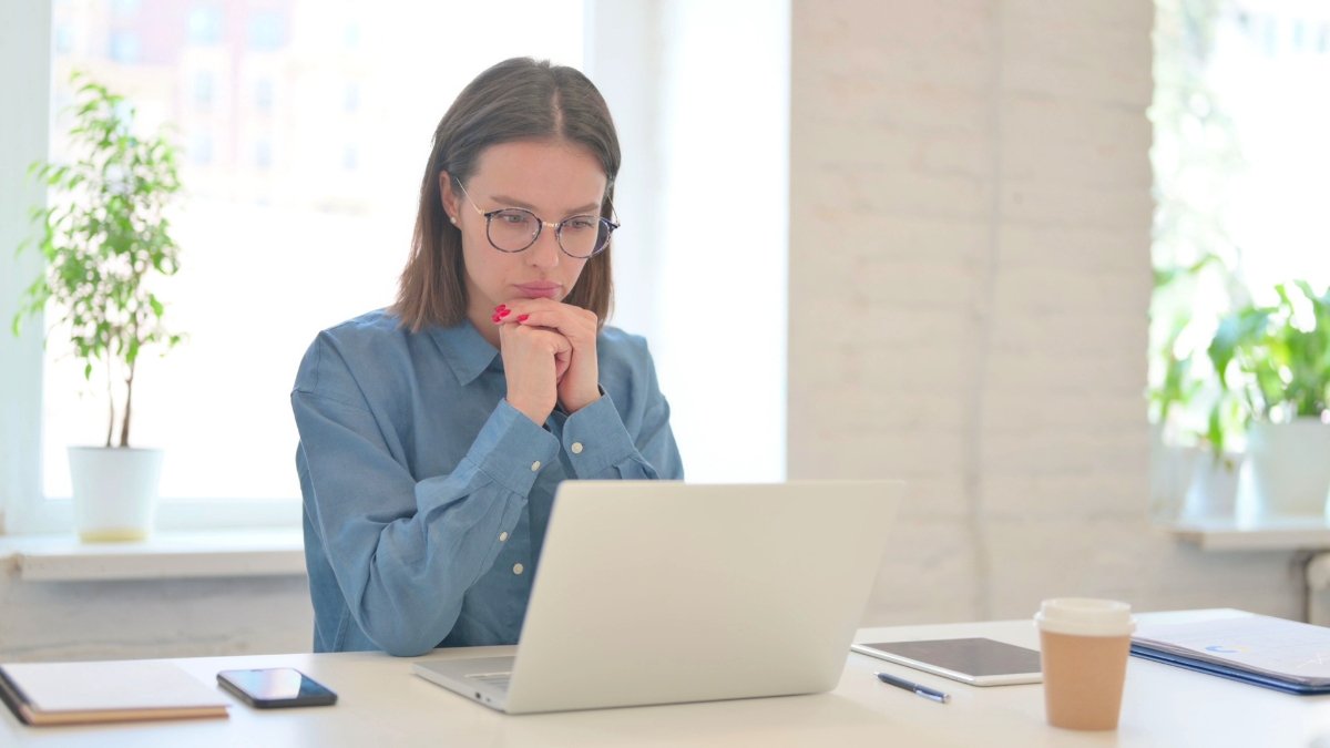 A woman thinking while looking at a laptop