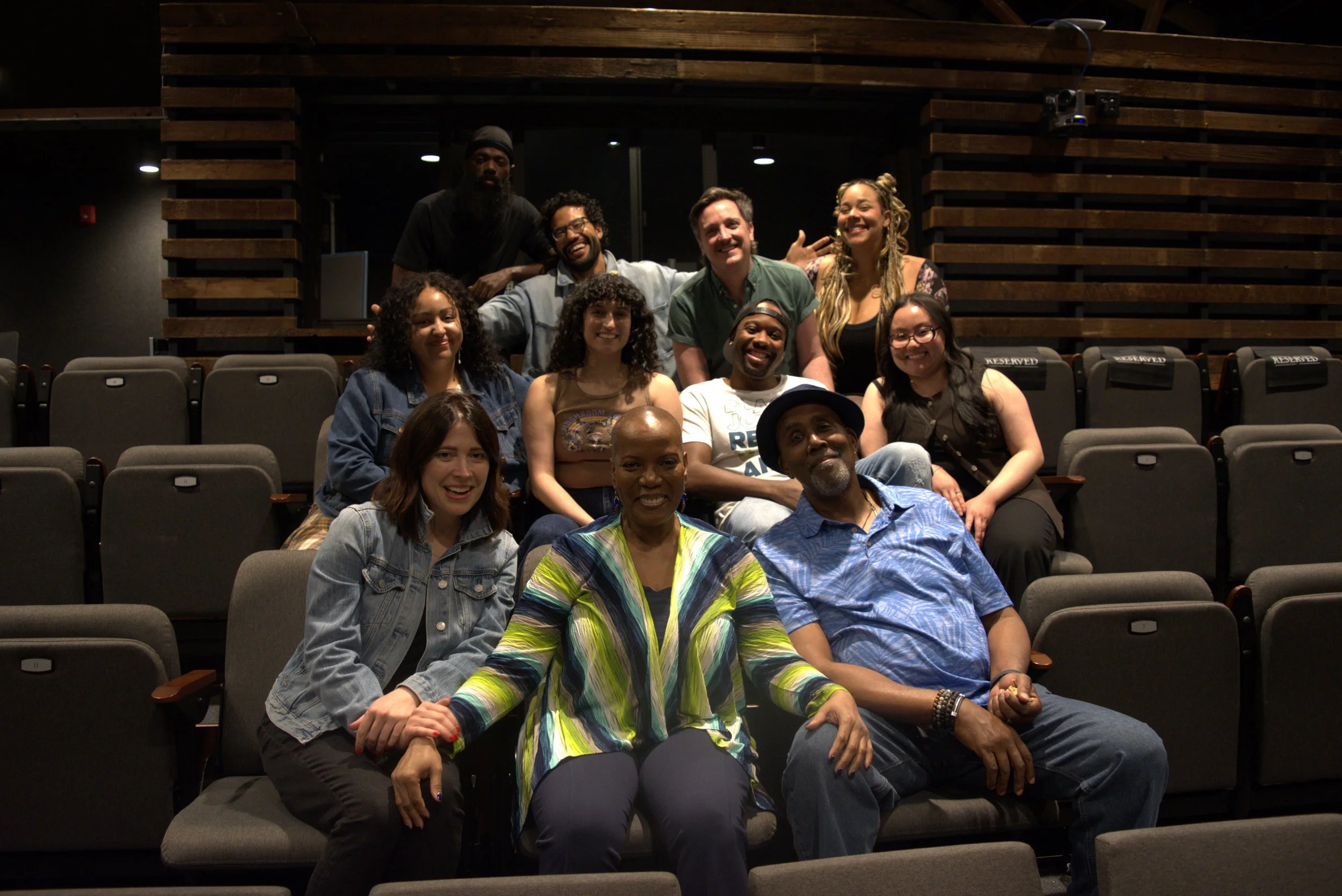 A diverse group of artists sitting in theater seats