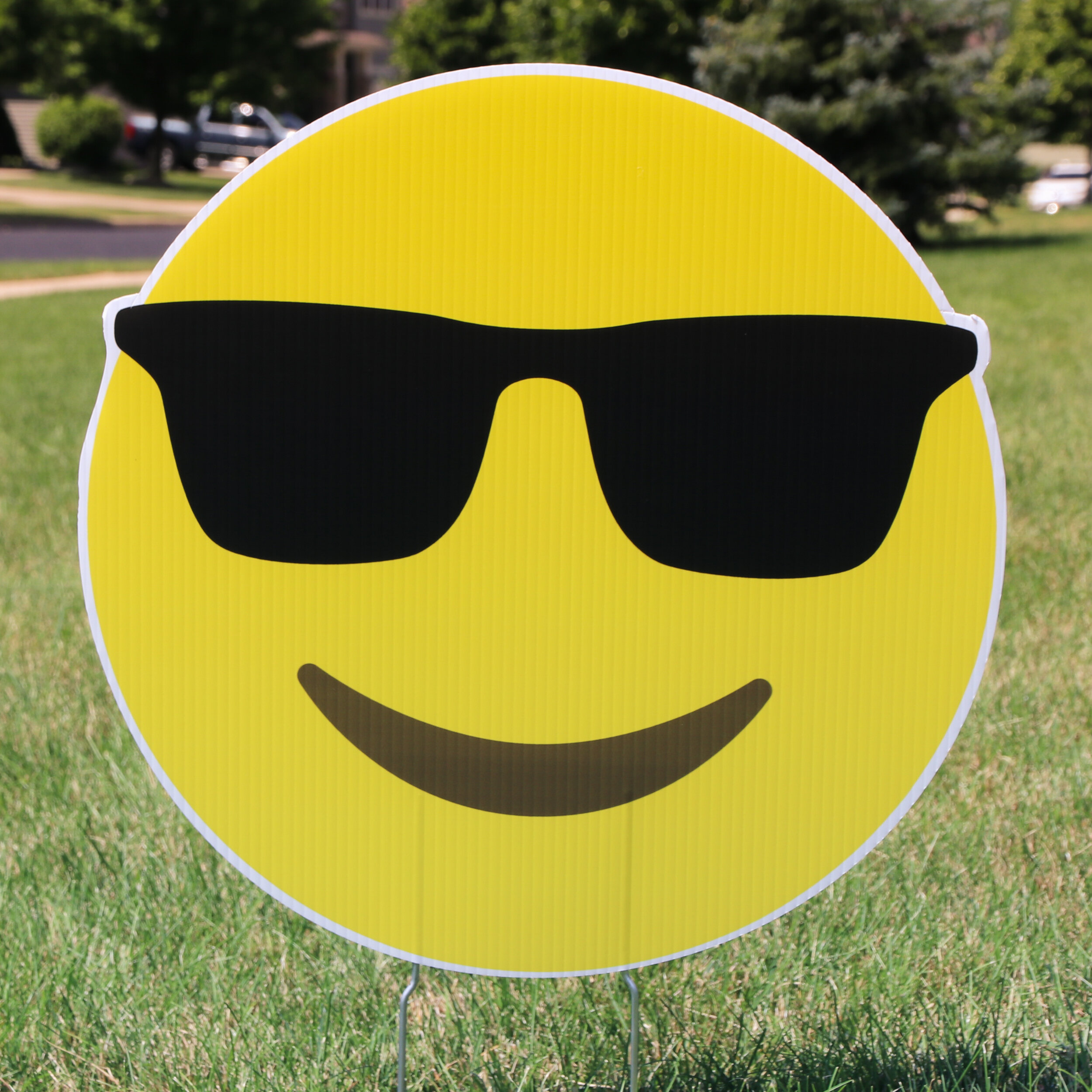 Yellow emoji face with sunglasses on grass