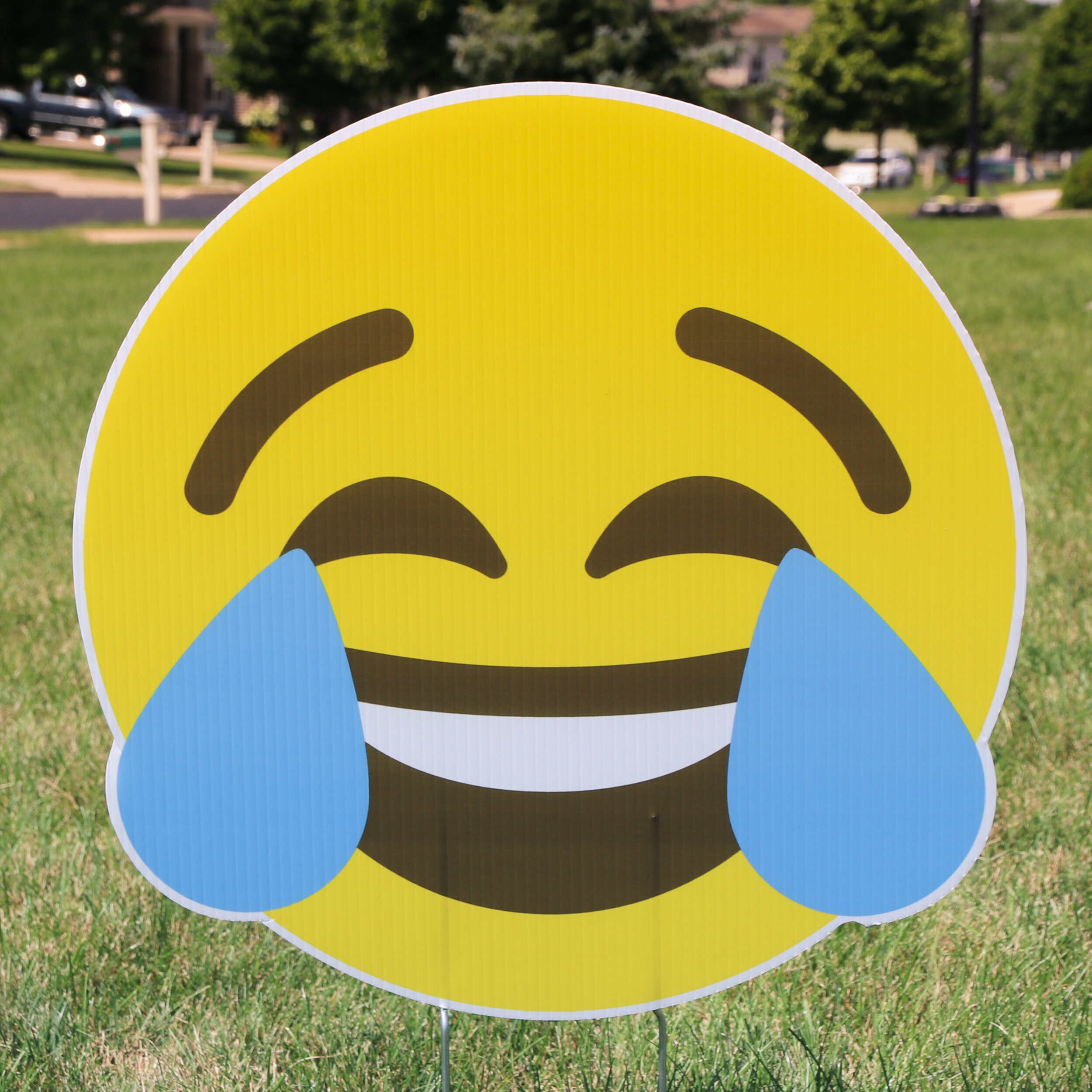 Lawn sign with laughing crying emoji on grass
