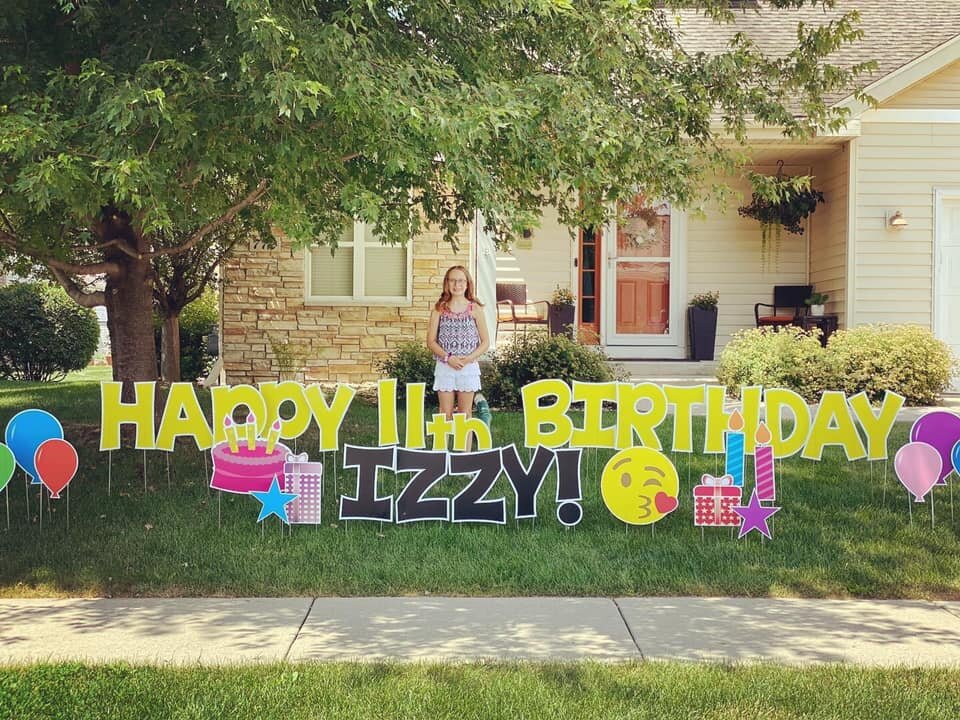 Girl standing in front of house with "Happy 11th Birthday Izzy" yard signs