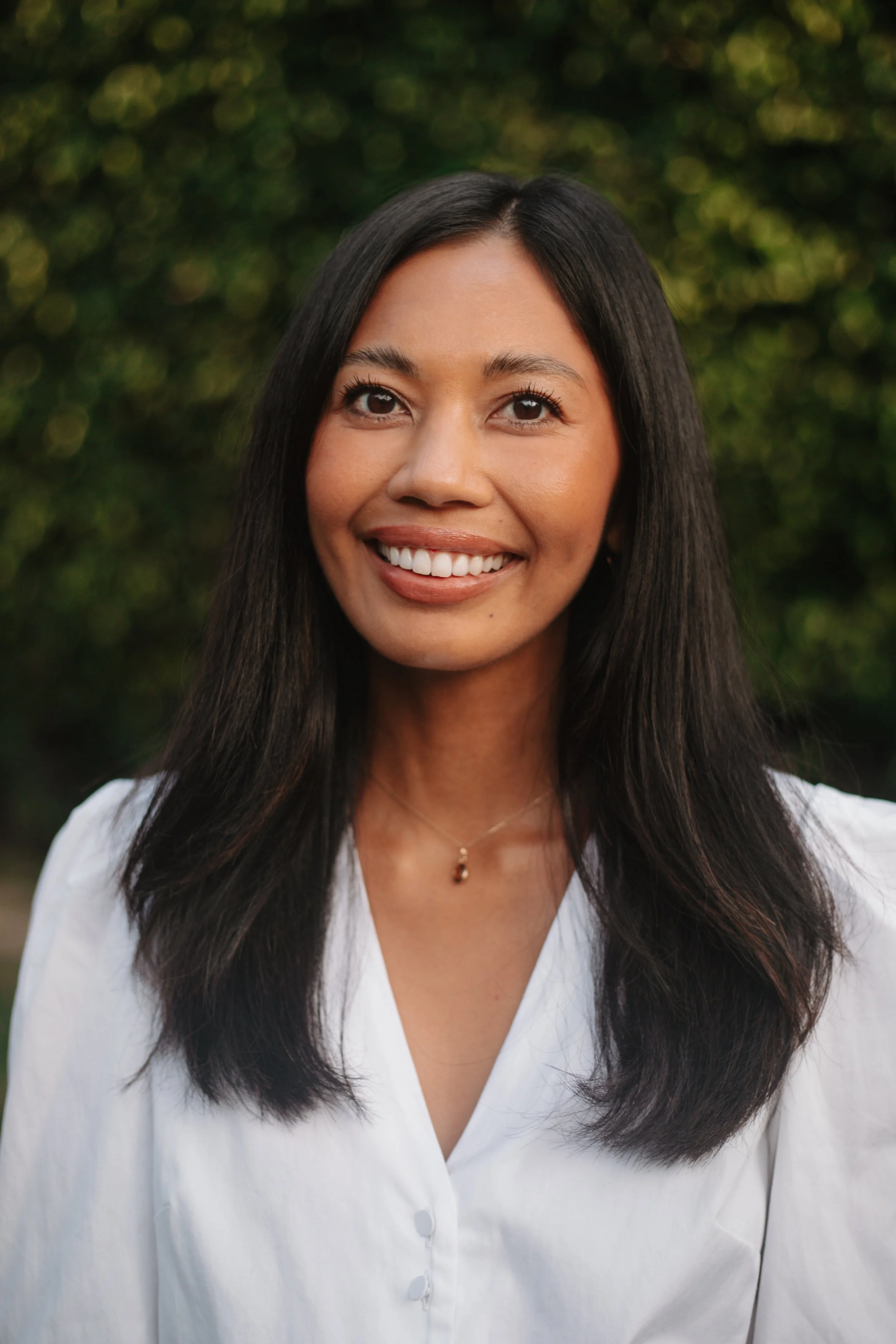 Jasper Estabillo, PhD, smiling outdoors in a white blouse