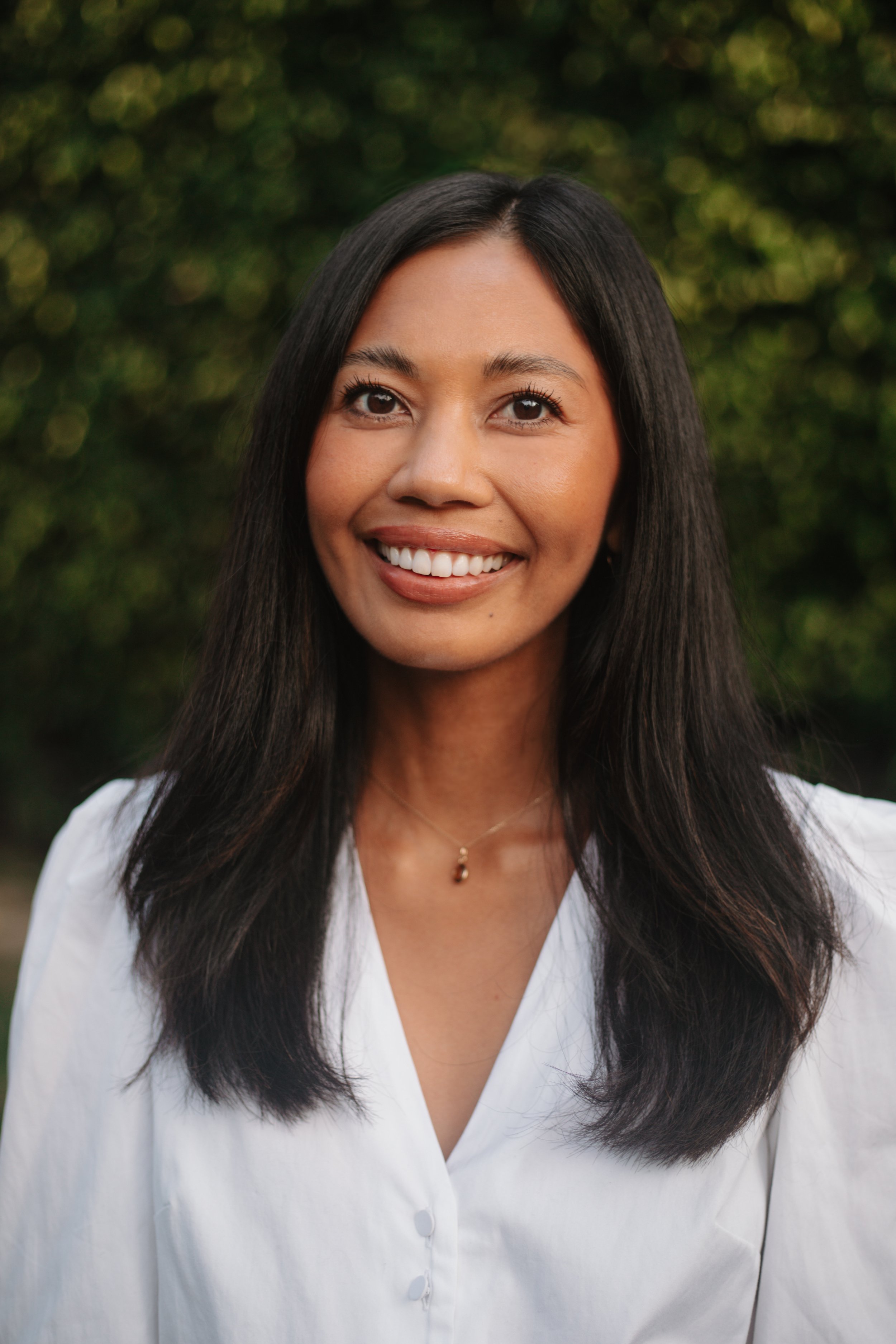 Jasper Estabillo, PhD, smiling outdoors in a white blouse