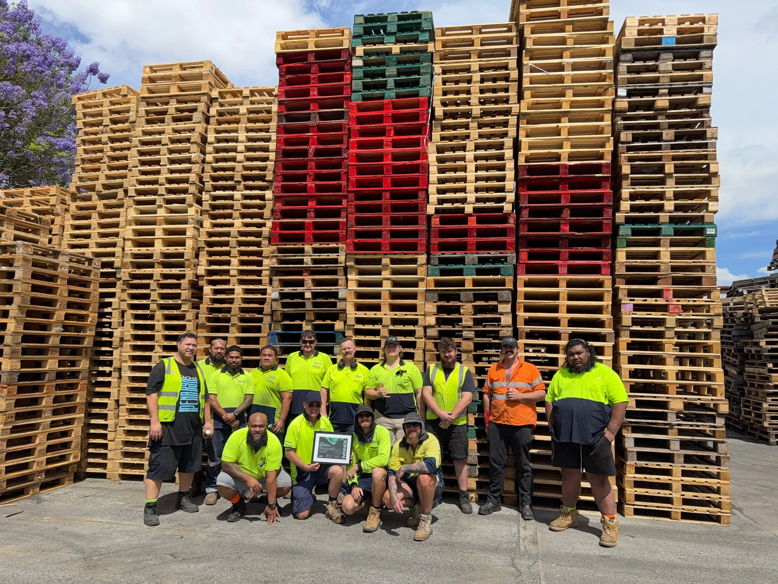 Team of Tom's Pallets standing in front of pallets, celebrating the LMBA award win
