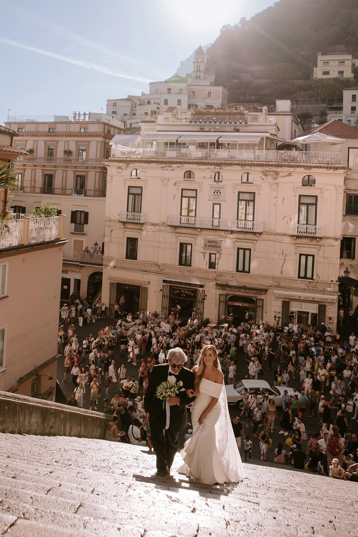 the bride is walking up the steps of Amalfi Cathedral