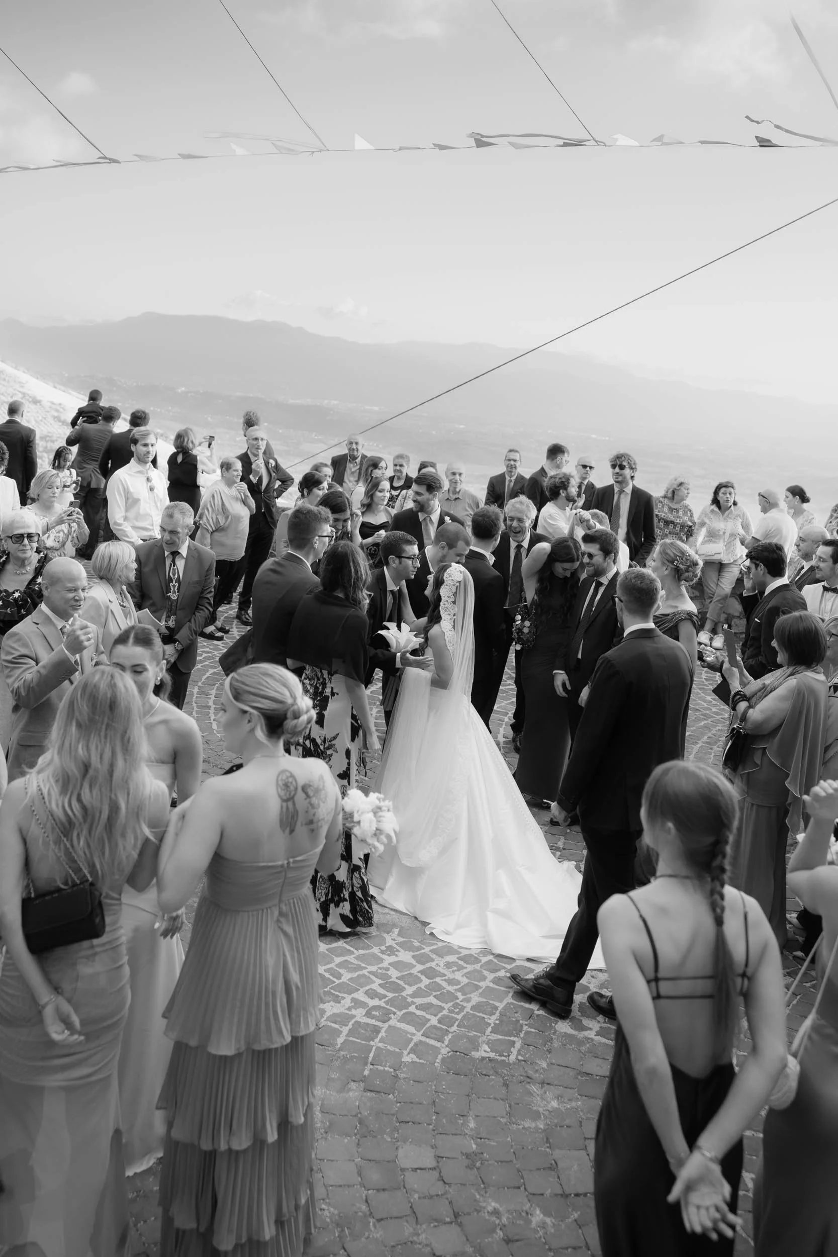 Italian bride greeting her guests outside of church. She's wearing a white bridal gown and a long cathedral veil