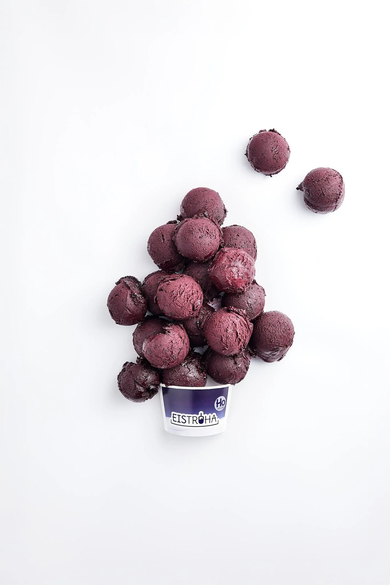 Lila gefrorene Kugeln in einem Becher mit dem Label 'Eistroha' auf weißem Hintergrund Fotografiert von Sarah Neuner.
