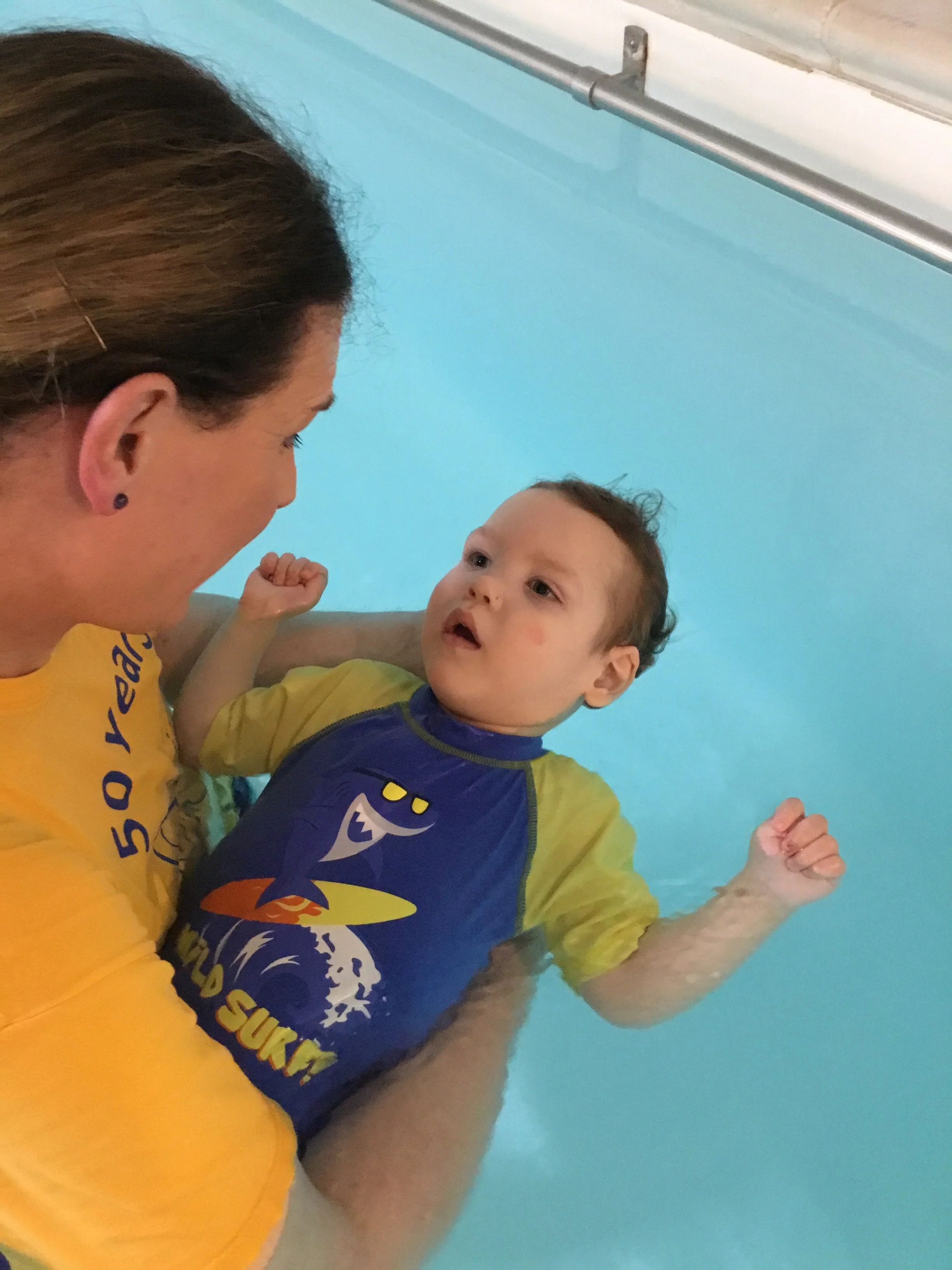 Young boy being held in swimming pool