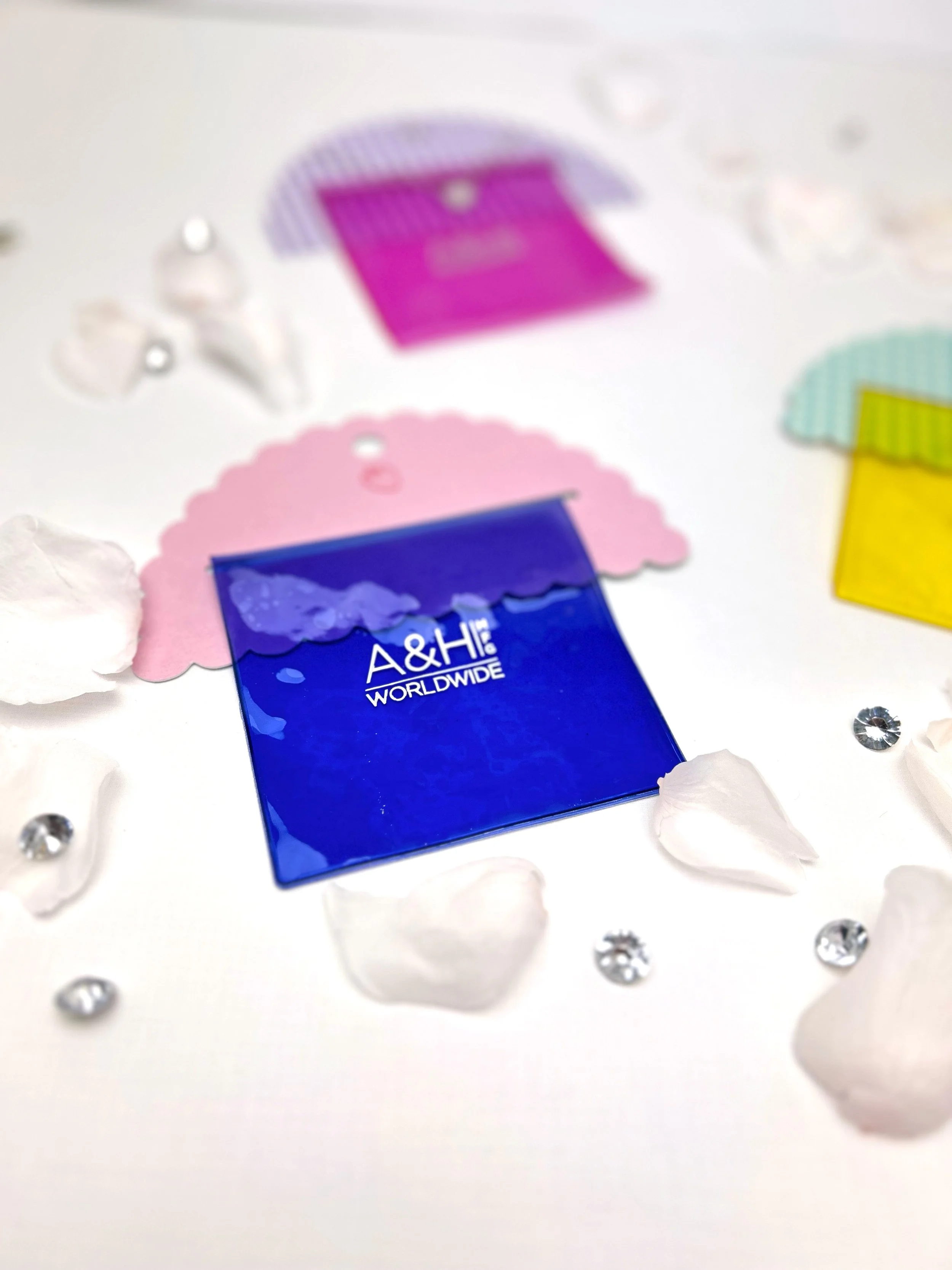 Blurred assortment of small colorful paper items and decorative rhinestones on a white surface.