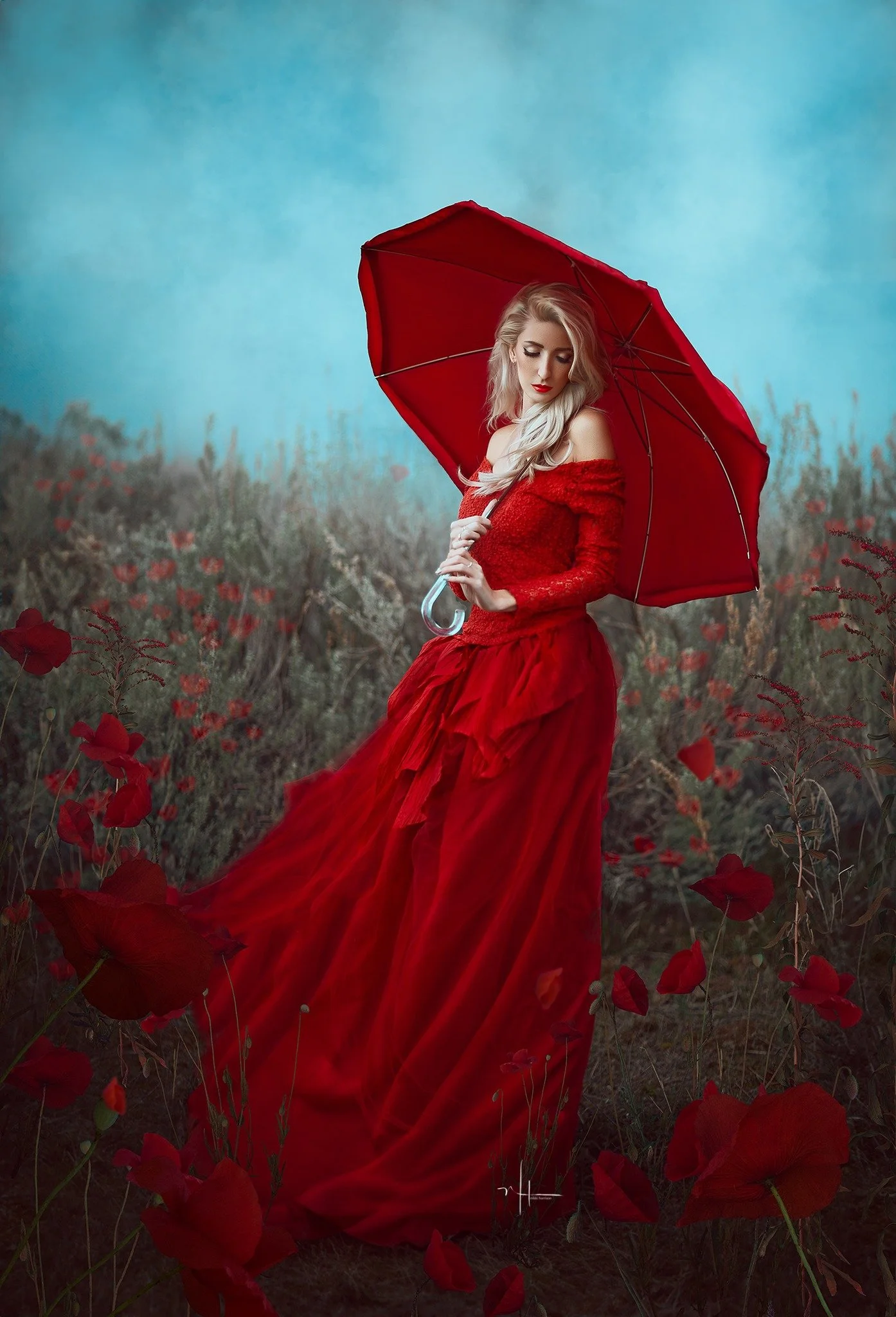 A woman in a flowing red dress holding a red umbrella stands amidst a field of red flowers with a cloudy sky background.