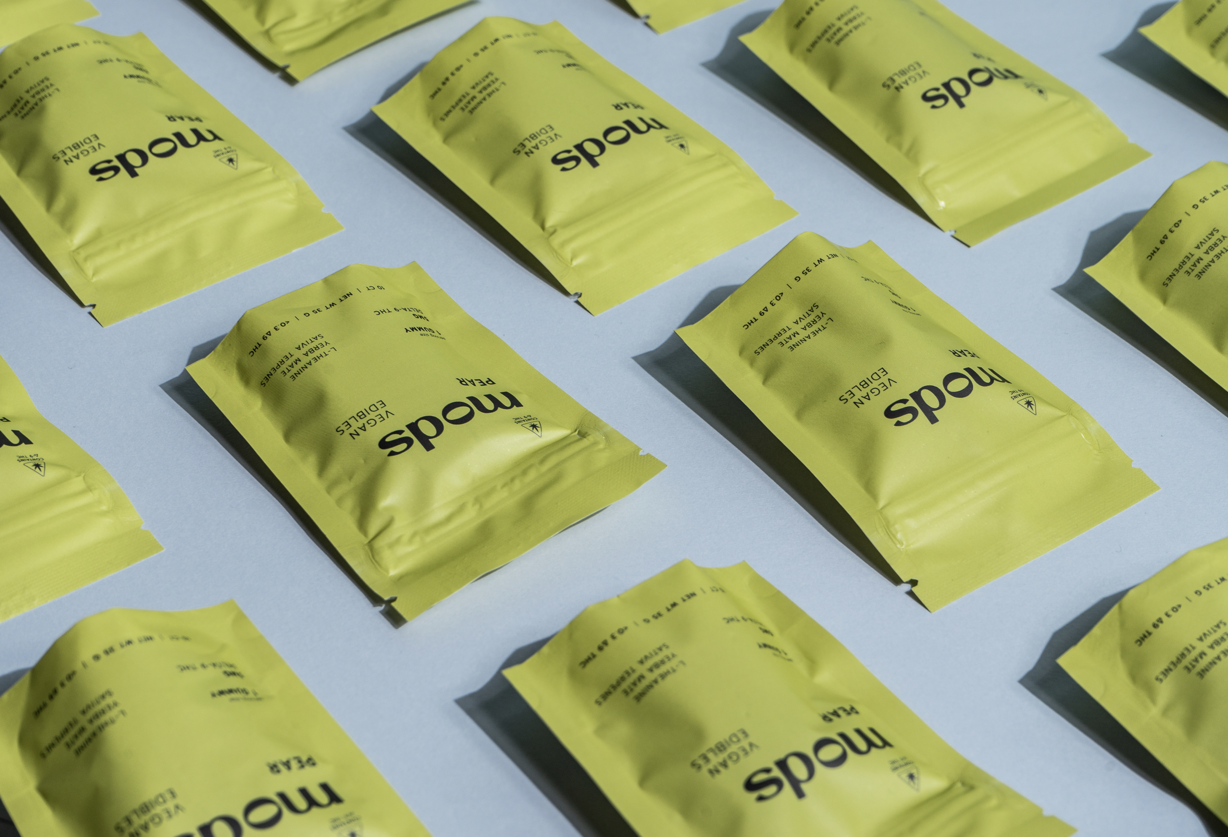 Multiple yellow vacuum-sealed pouches labeled 'Meds' and 'Vegan Edibles' arranged on a white surface.