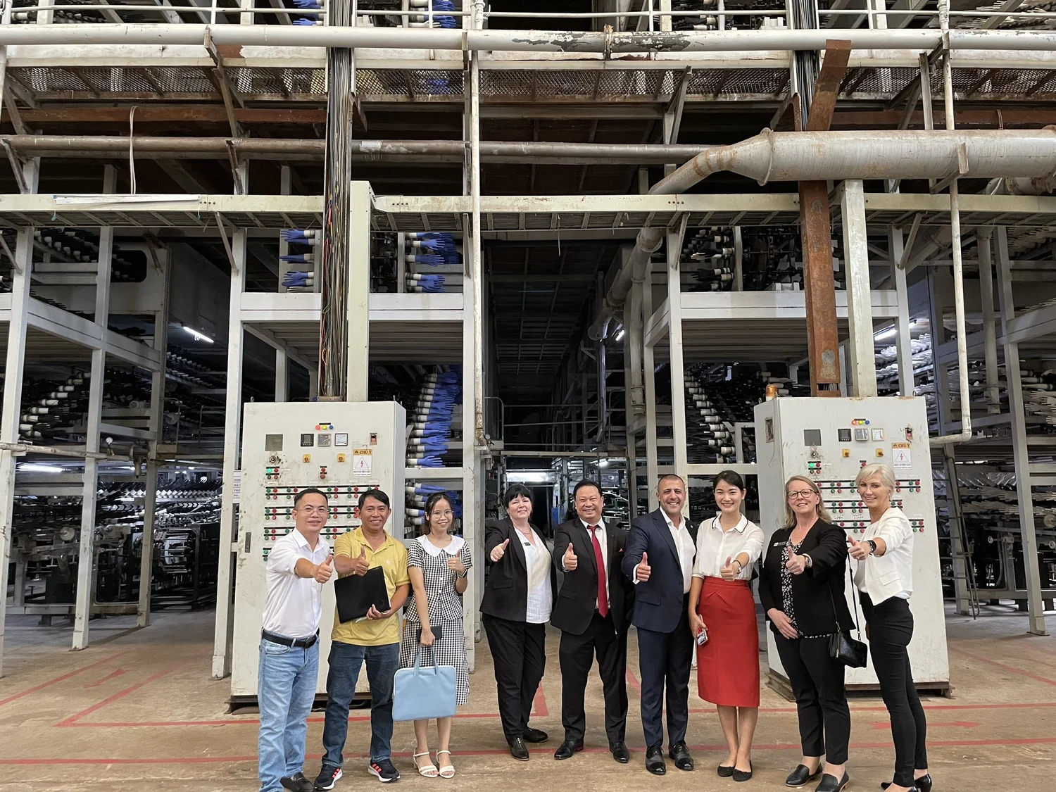 Cosmo Sourcing team and clients giving a thumbs up inside an industrial plant
