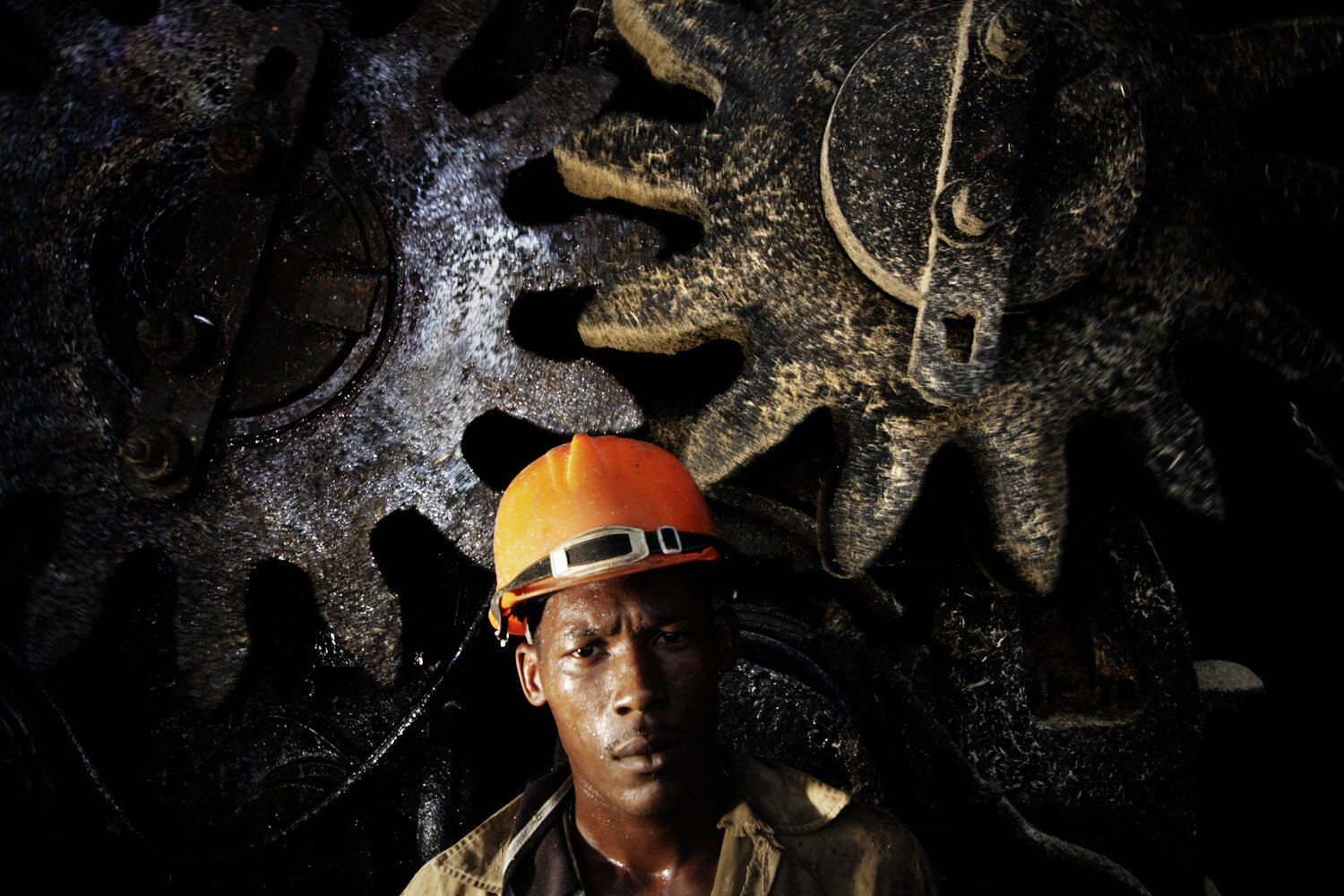  Yoandri, 28, poses for a portrait  in front of giant cogwheels in a sugarcane factory. Duani has been working for 2 year  in the sugarcane industry.  