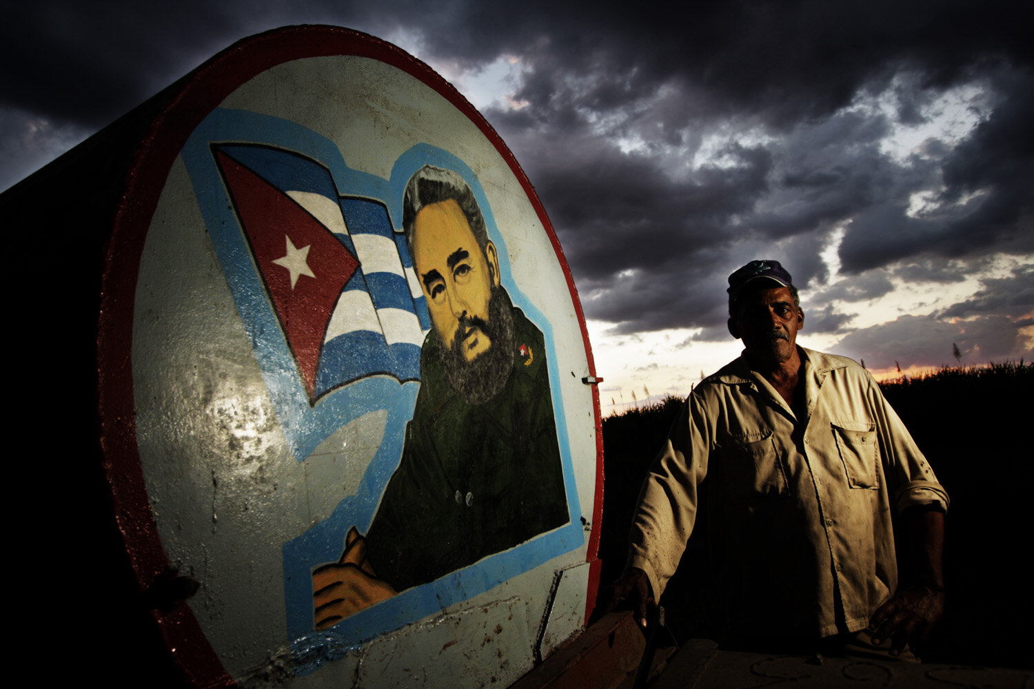  Osmel, 60, welder, poses for a portrait next to a water tank that bears an image of Cuba´s Revolution leader Fidel Castro. Osmel has been working for 35  years in the sugarcane industry.  