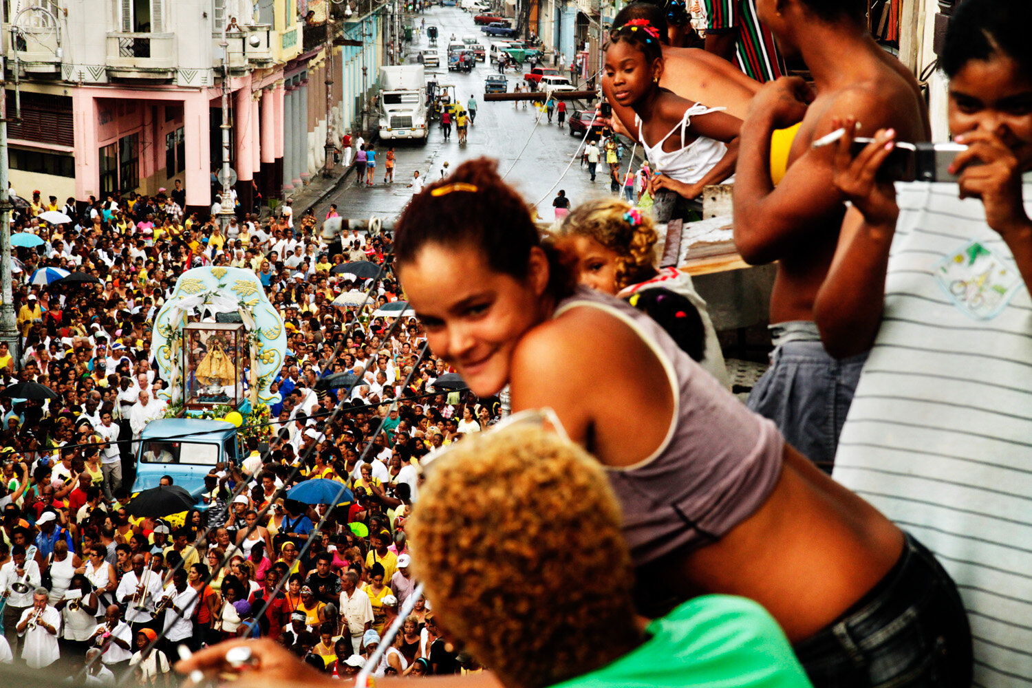  Cubans watch from a balcony as they worship the Virgen de la Caridad de Cobre, Cuba’s national saint, during a procession in Centro Habana, 2010                      