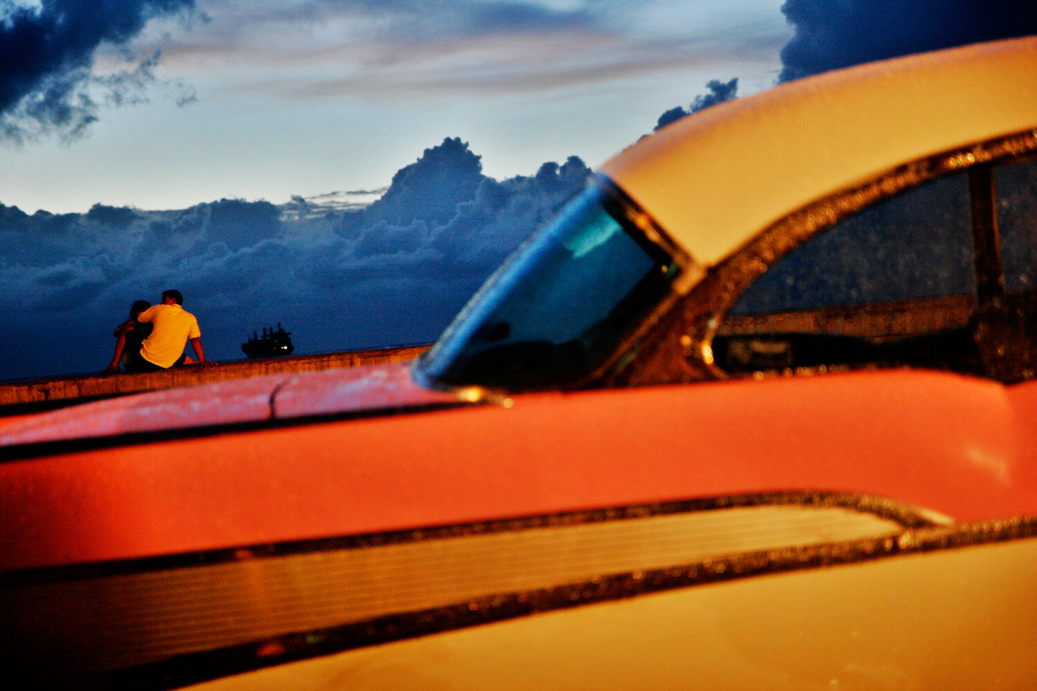  Cuban couple romancing at the Malecon, classic car in the foreground. 