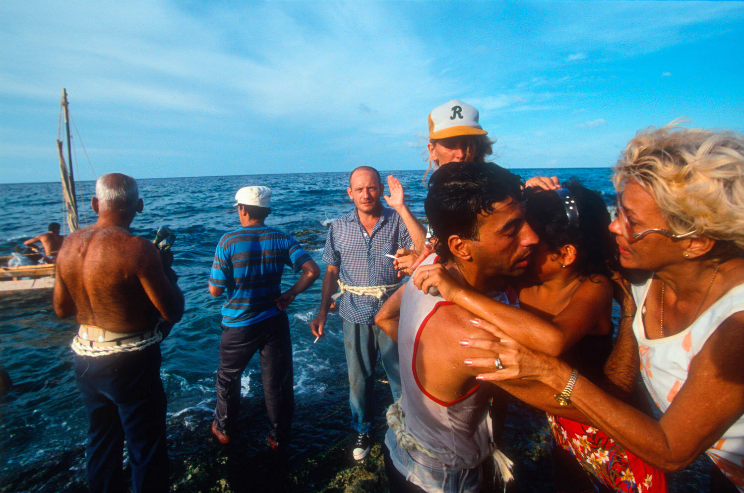  A young man is being kissed goodbye by his family as he is leaving Cuba. 