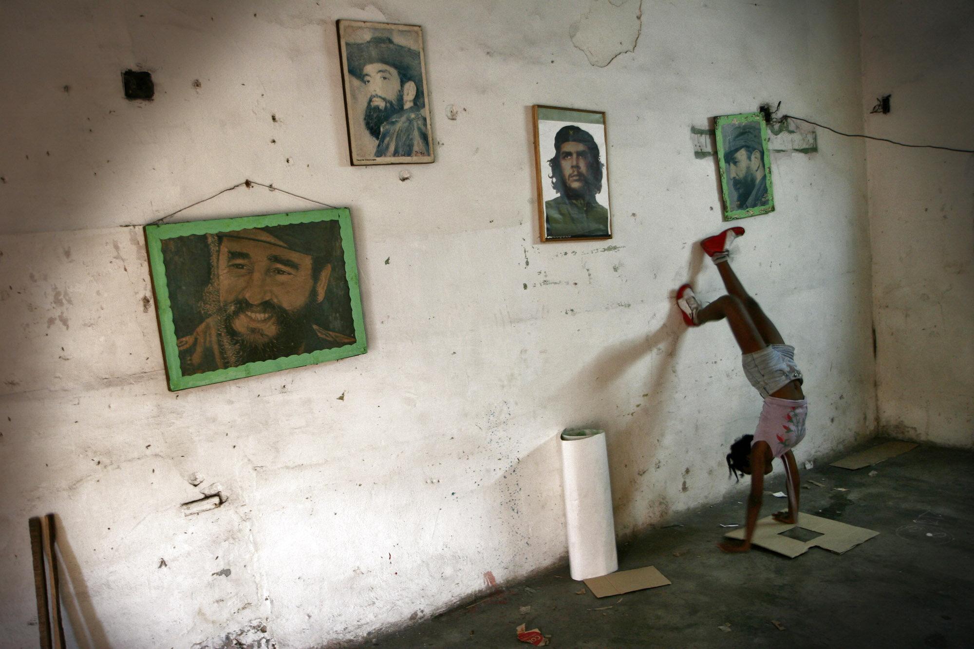  A cuban girl plays in a local CDR, with the photos of Fidel Castro (left and right), Revolution Commander Camilo Cienfuegos (2nd left) and Che Guevara (2nd right) at the wall, 2007.                    