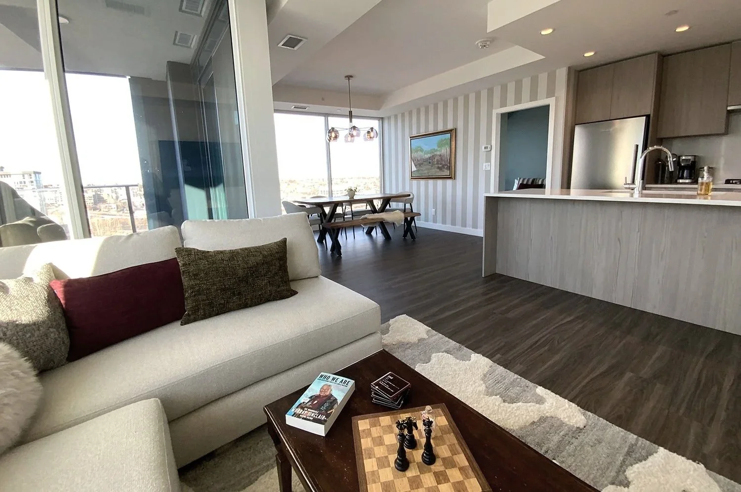 This eclectic condo design mixes antique furnishings with modern elements and striped wallpaper, creating a warm, stylish living space with stunning wraparound city views