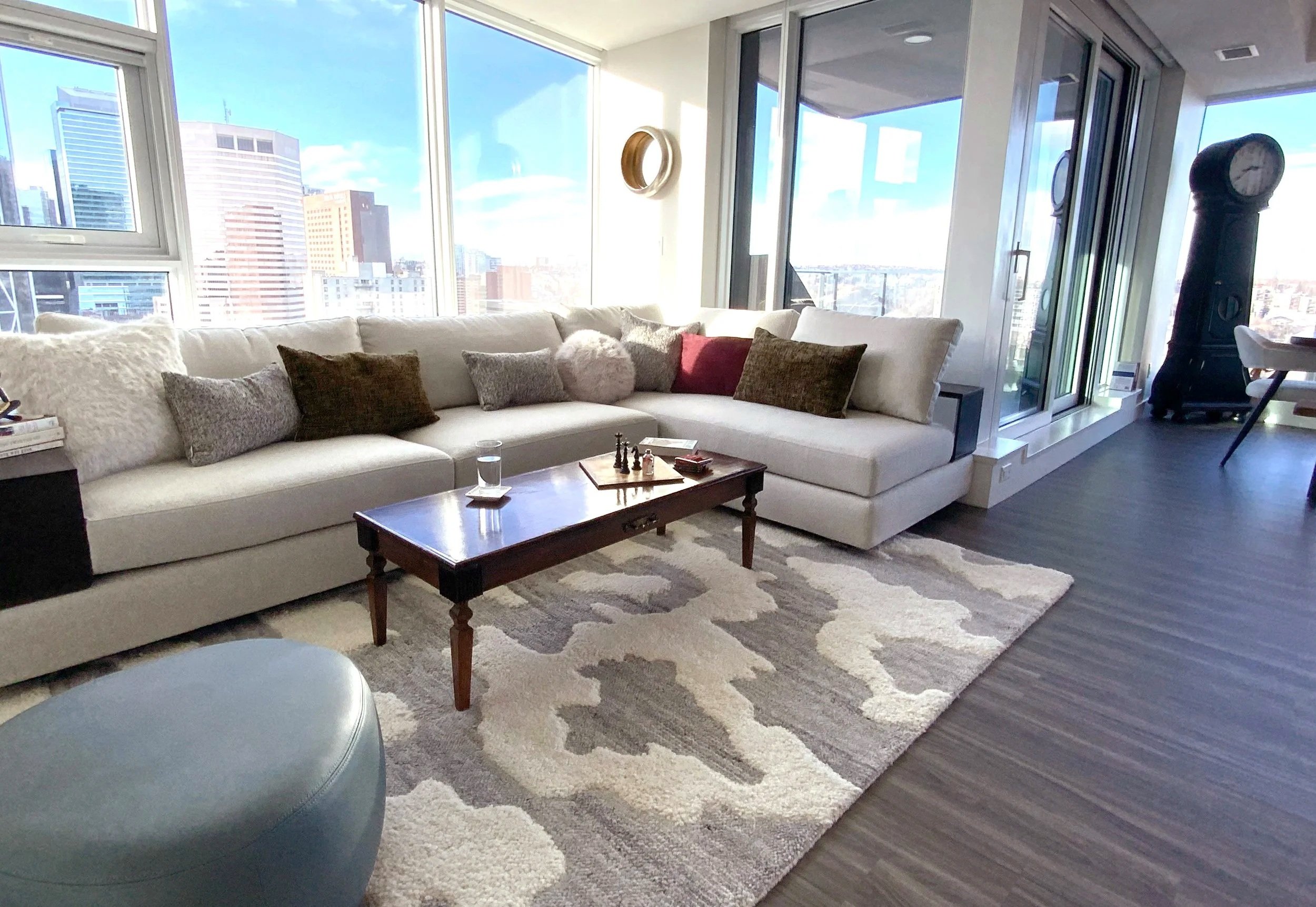 Light neutral furnishings, warm wood tones, and soft colourful accents create a comfortable seating area designed to showcase the city skyline views.